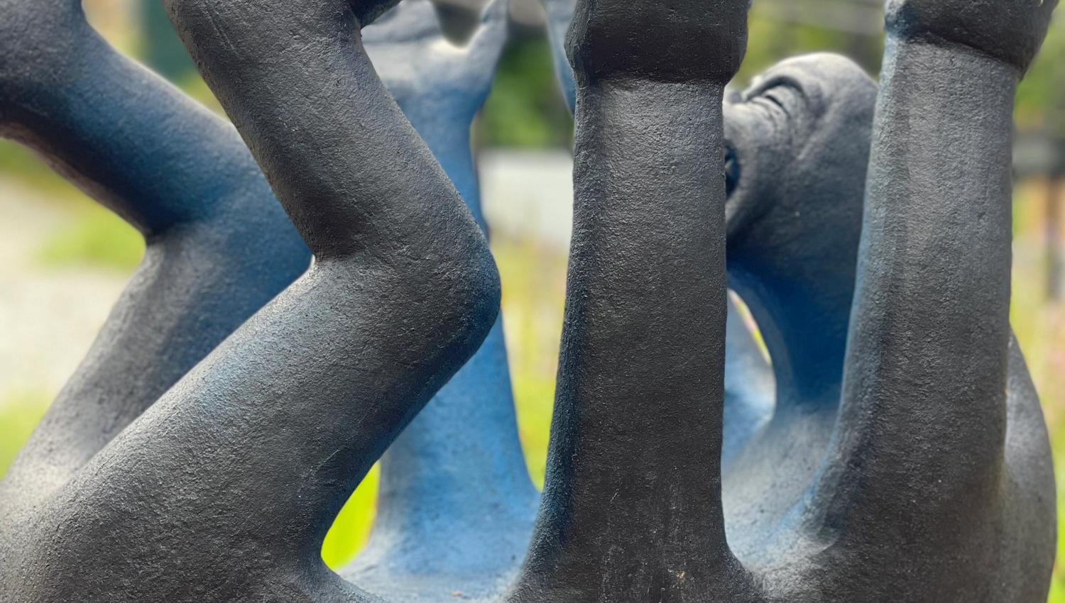 svart skulptur som ser ut som en lite menneske med mange armer og ben