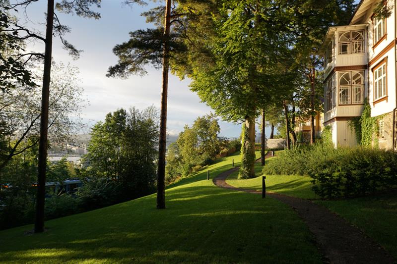 A trail alonng the trees by an old wooden house.