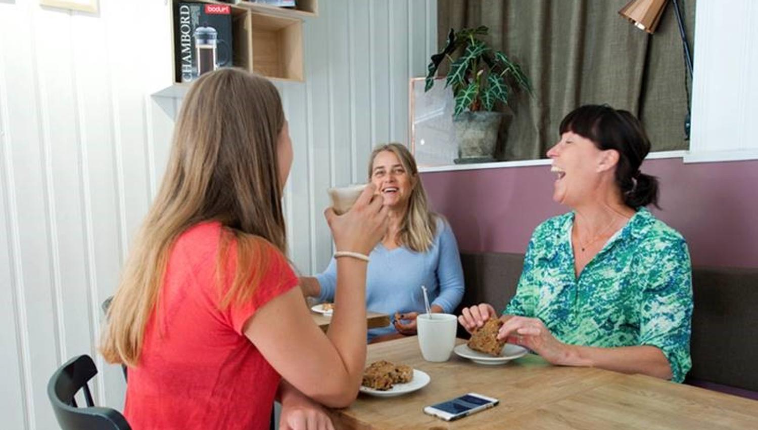 Damer som drikker kaffe og spiser bakst