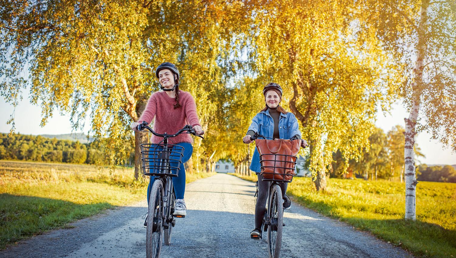 2 ladies on bike down the allee from Fæby Brewery in Verdal