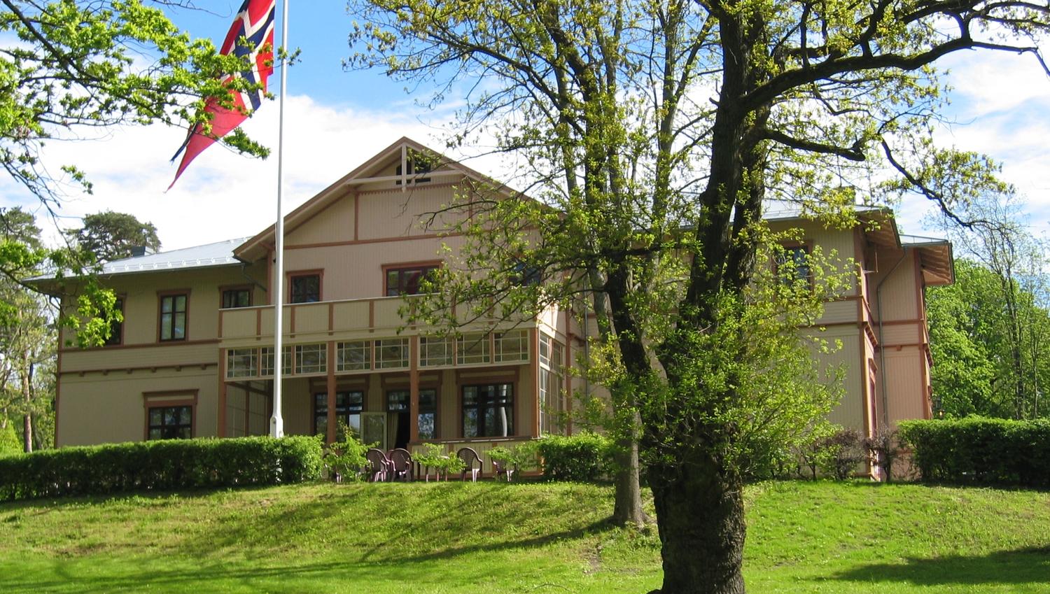 The hotel with a green lawn and a flagpole in the foreground.