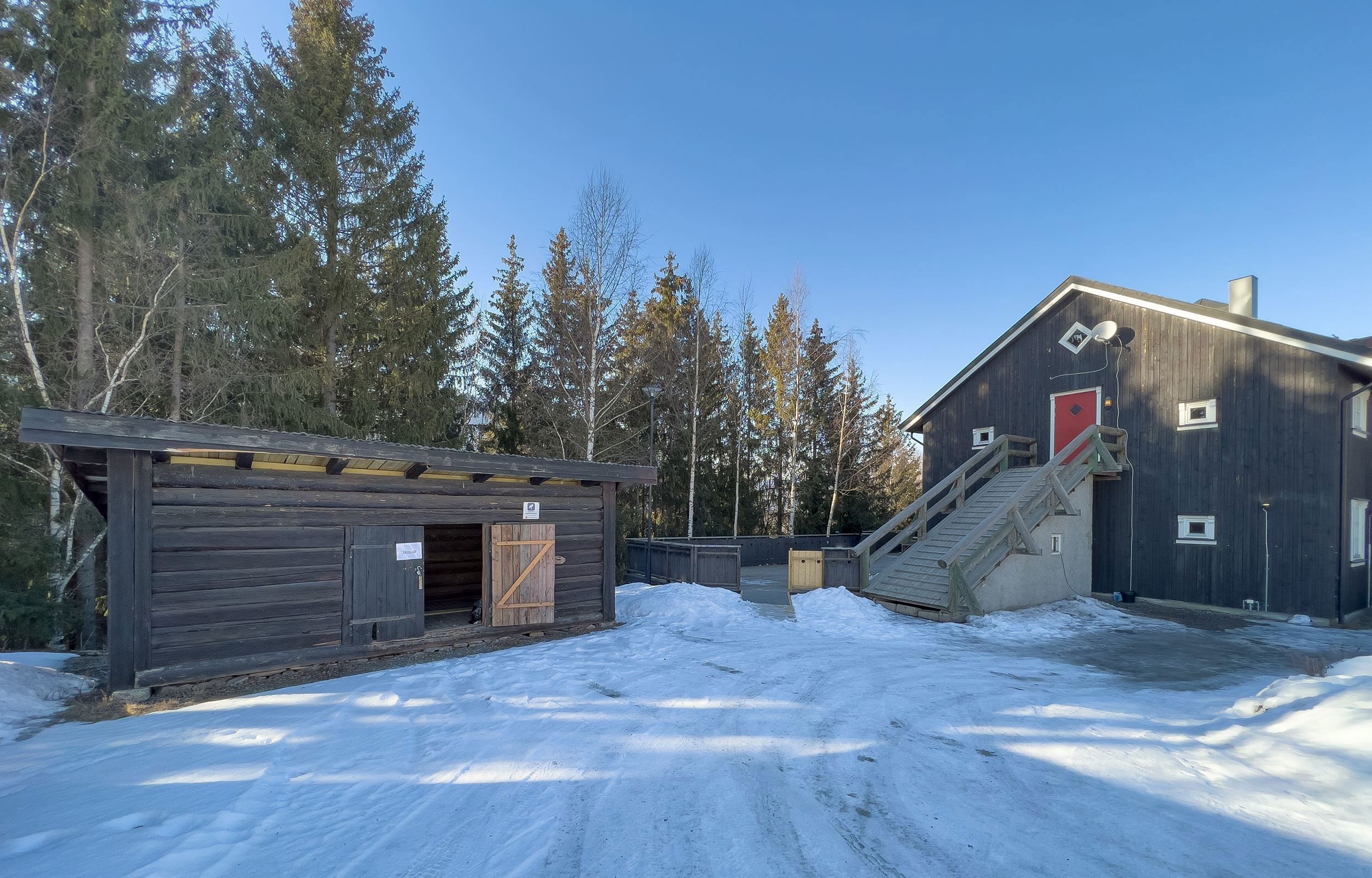 A building with stairs and a ski shed in the snow.