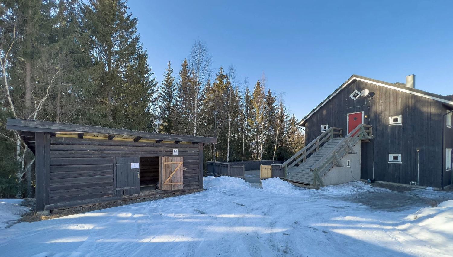 A building with stairs and a ski shed in the snow.