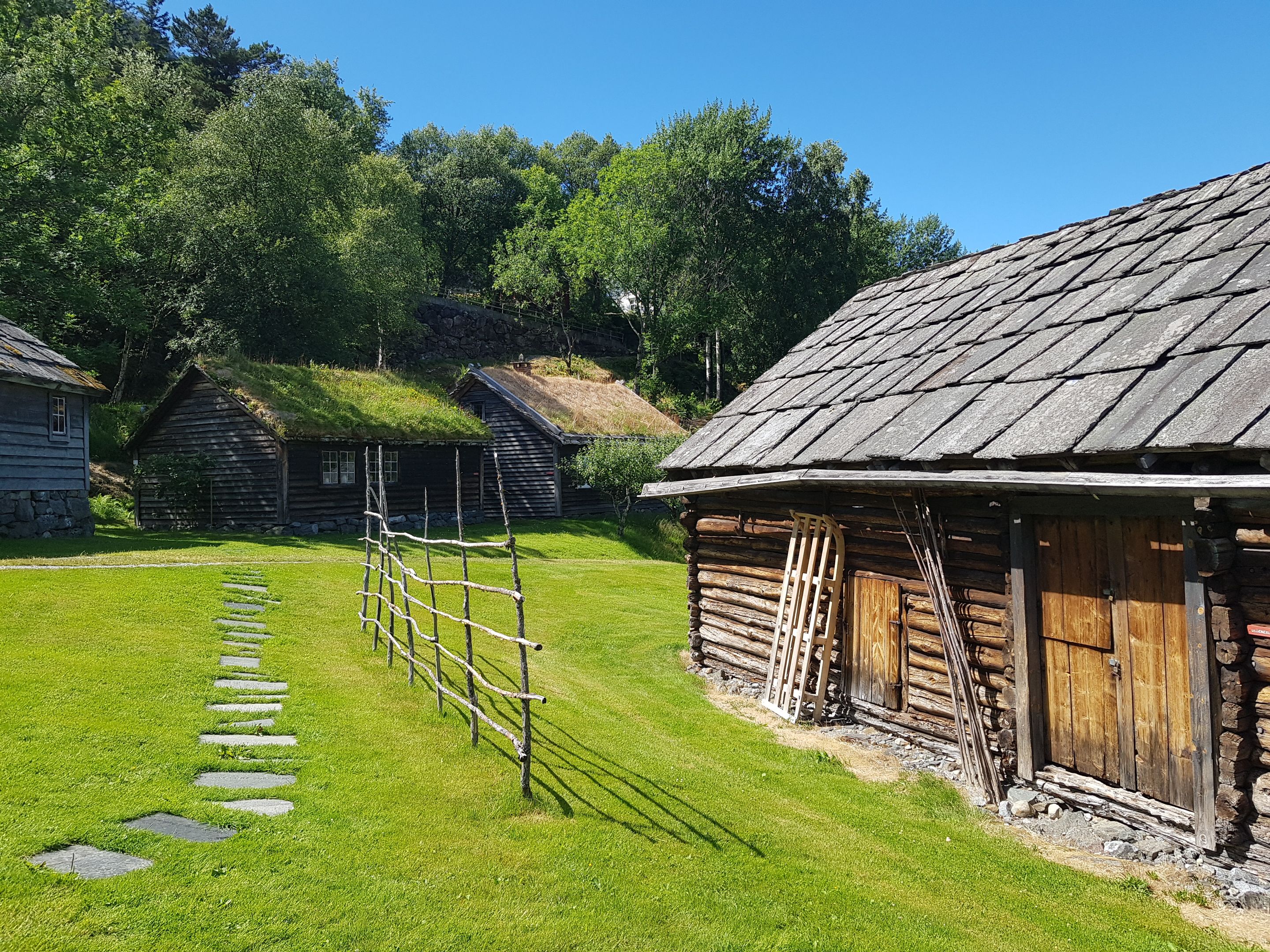 Tradisjonelle trehus med torvtak og grindgjerde på friluftsmuseet i Hardanger.