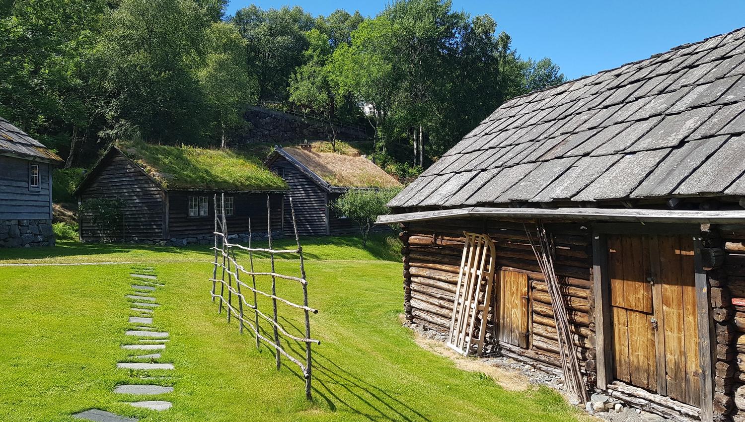 Tradisjonelle trehus med torvtak og grindgjerde på friluftsmuseet i Hardanger.