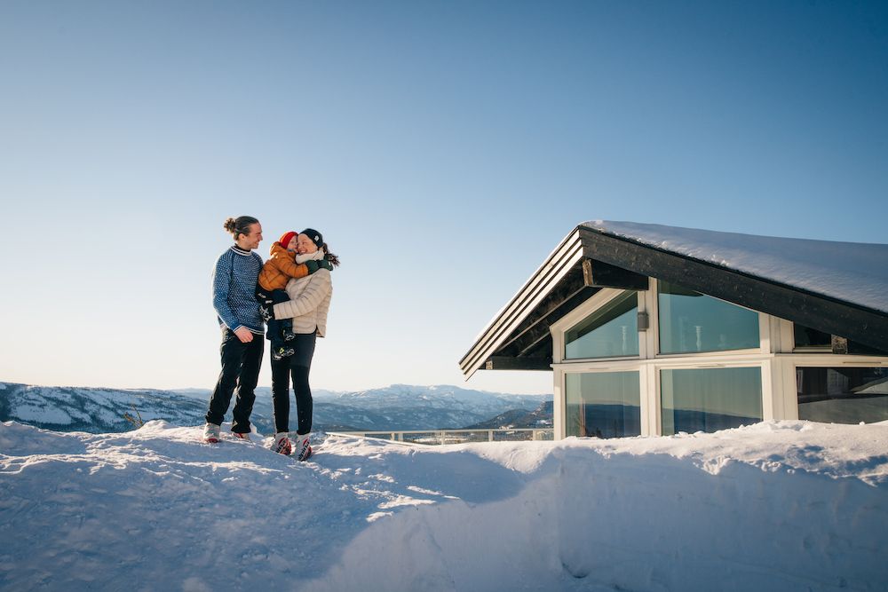 par med barn står foran en hytte på Lifjell Tunet om vinteren
