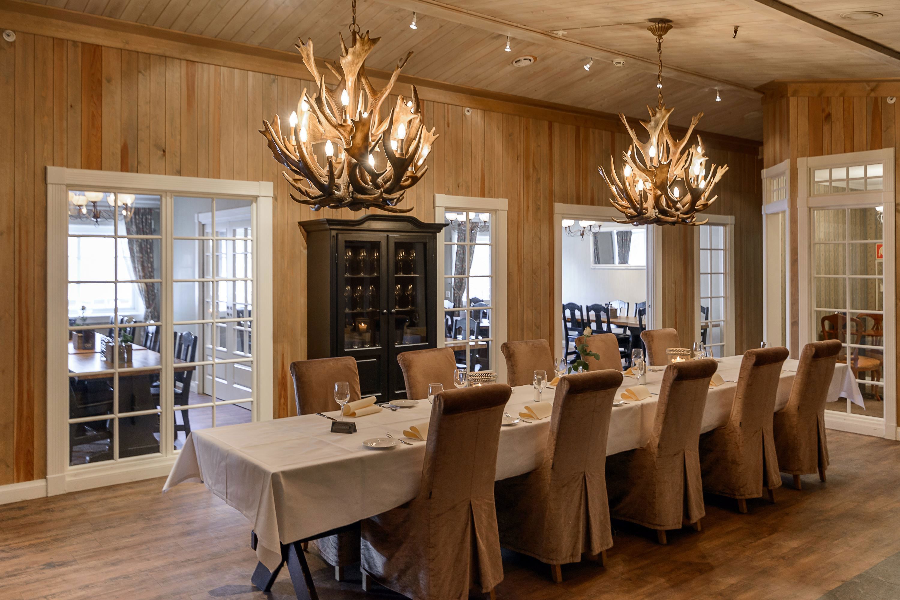 A long table with chairs and chandeliers in a room.