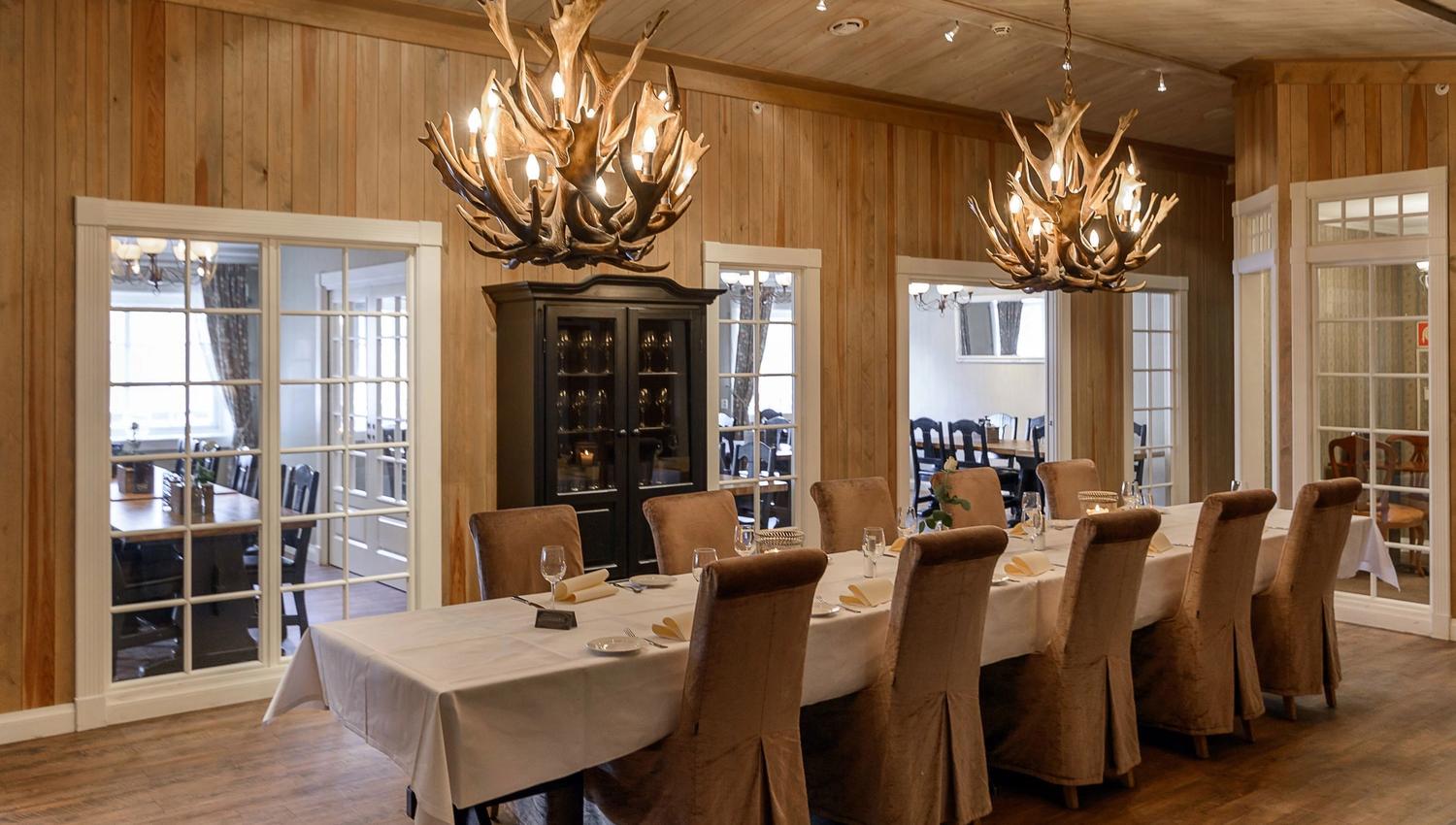 A long table with chairs and chandeliers in a room.