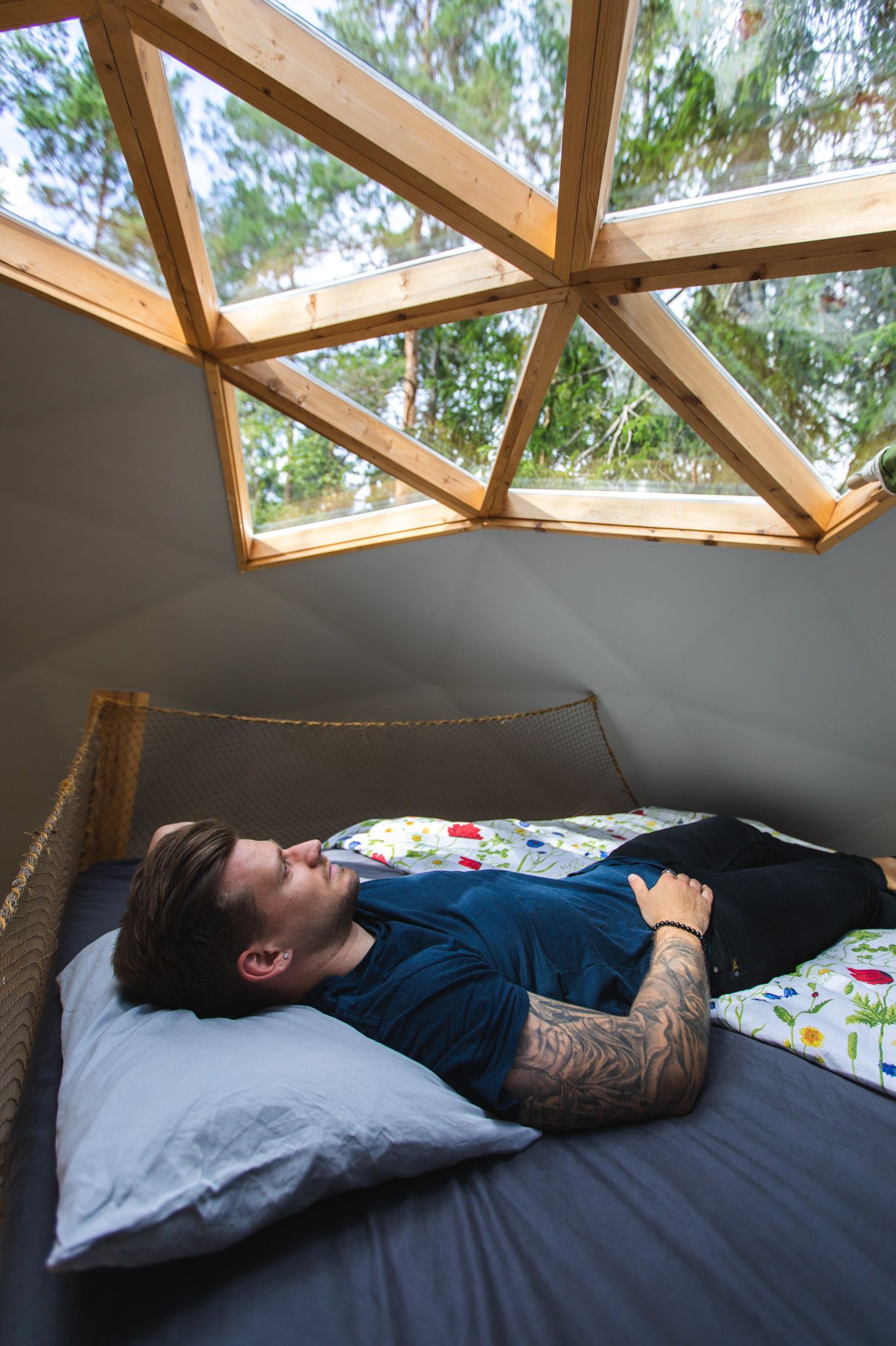Man laying on the bad and looking through the roof window