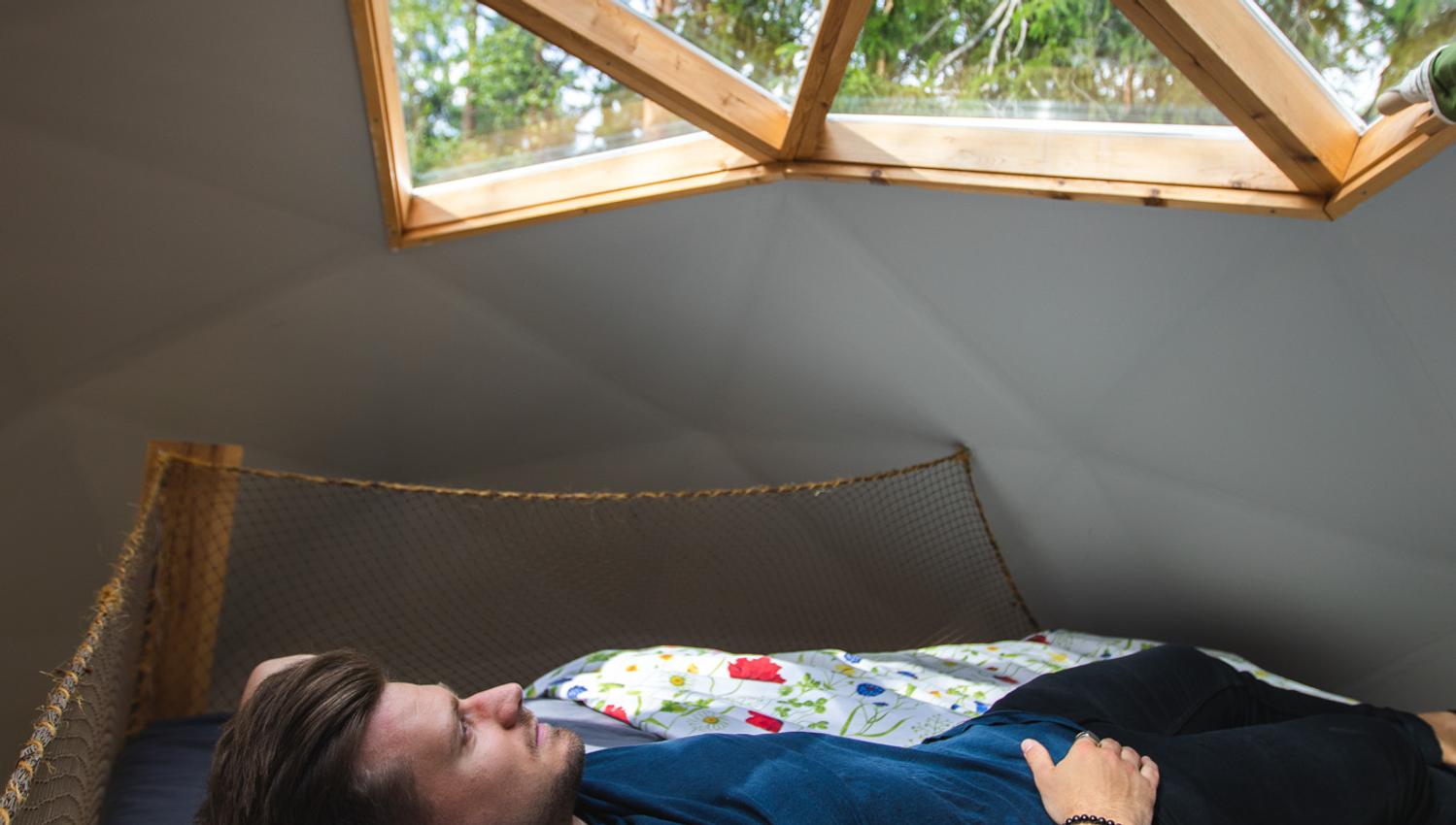 Man laying on the bad and looking through the roof window