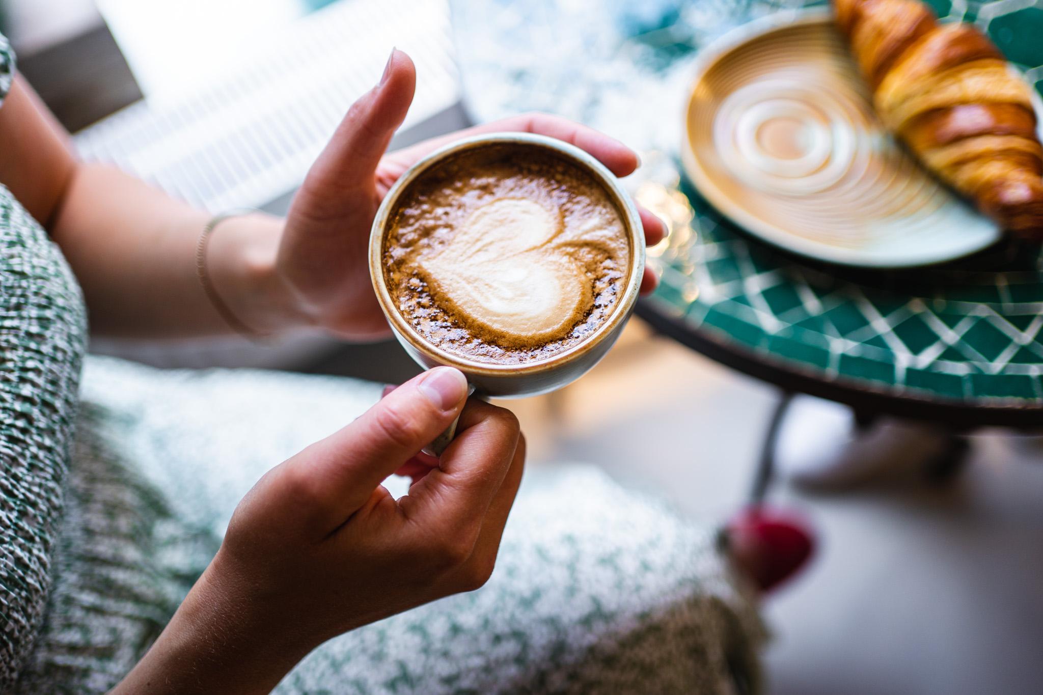 dame som holder en kaffekopp med kaffe og skum