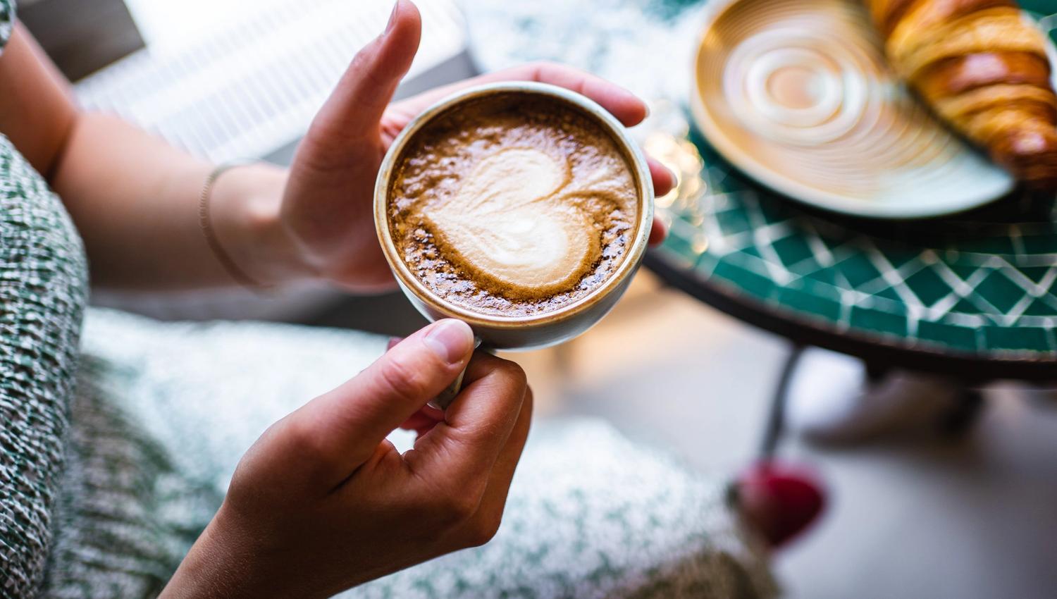 dame som holder en kaffekopp med kaffe og skum