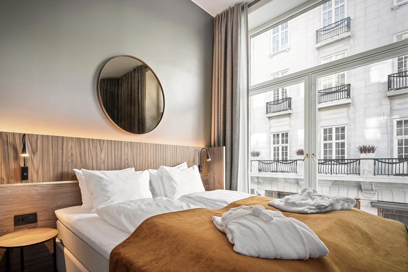 Room interior with a double bed and large windows.