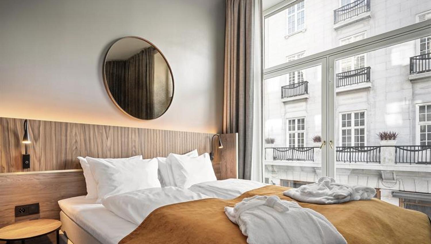 Room interior with a double bed and large windows.