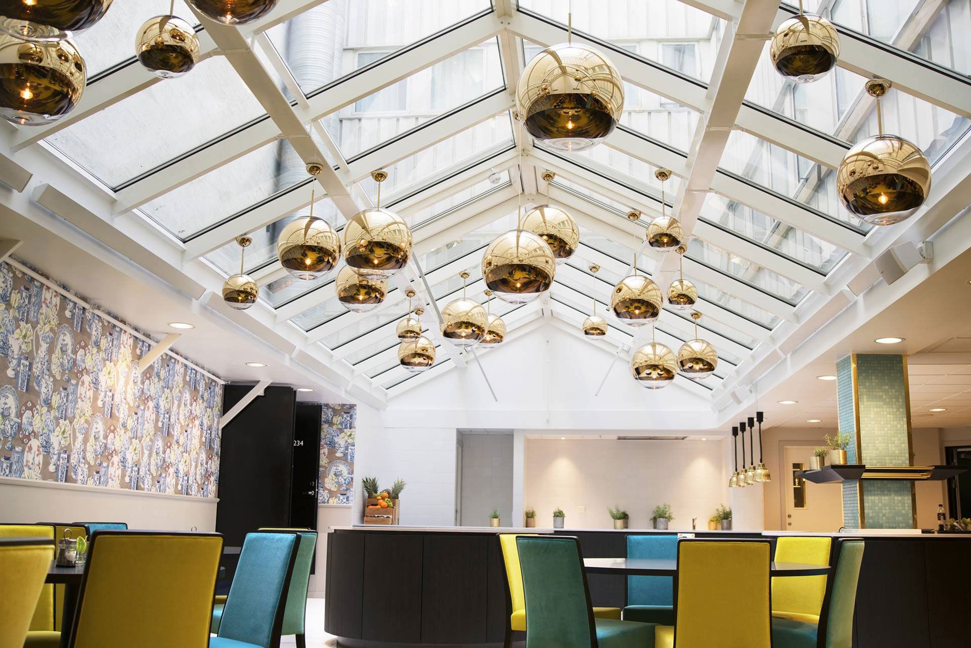 Lobby at Thon Hotel Terminus. Seating areas in blue and yellow. Golden ceiling lights. Photo
