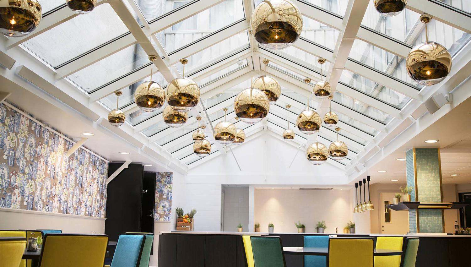 Lobby at Thon Hotel Terminus. Seating areas in blue and yellow. Golden ceiling lights. Photo