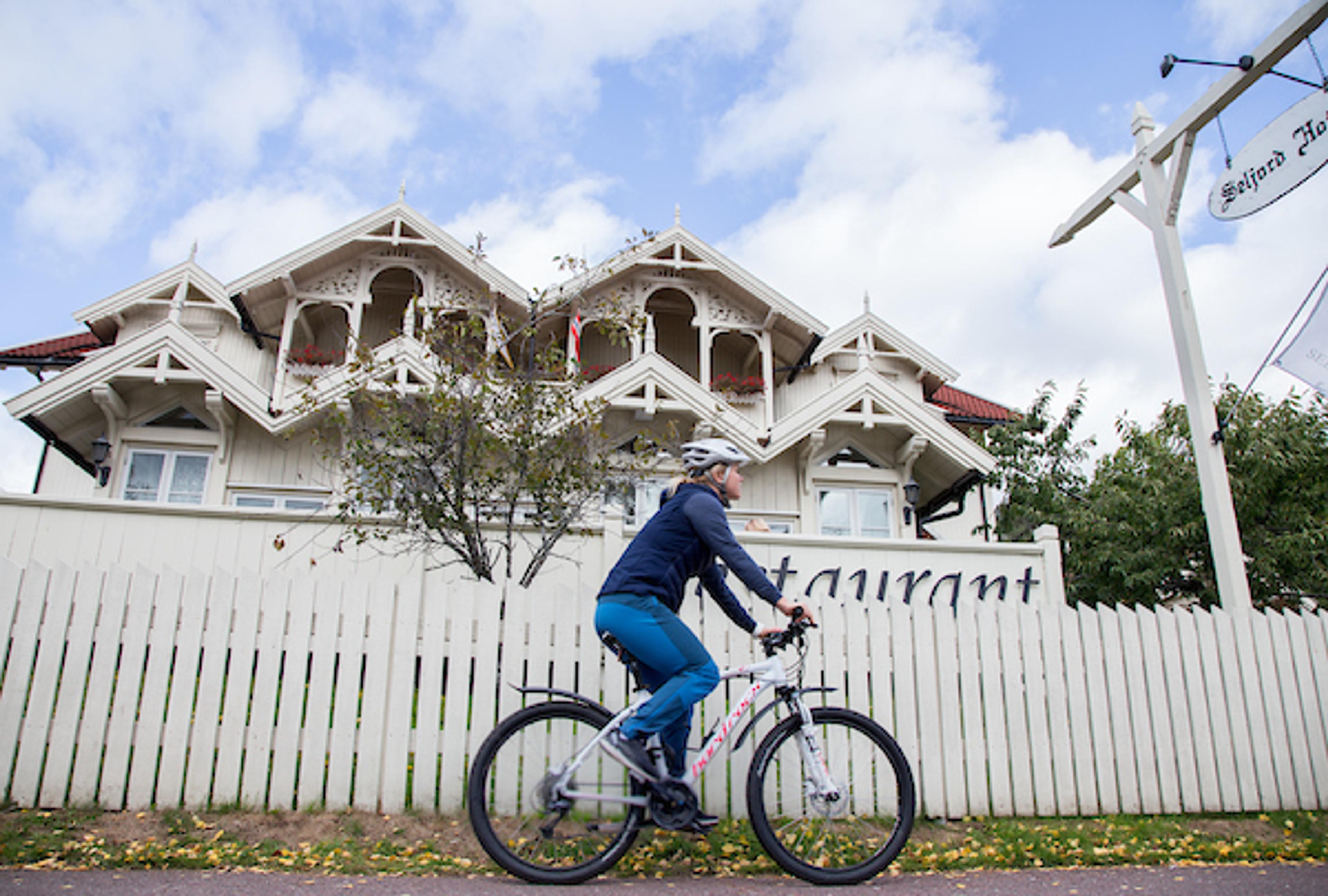 syklist sykler forbi et hus i Seljord
