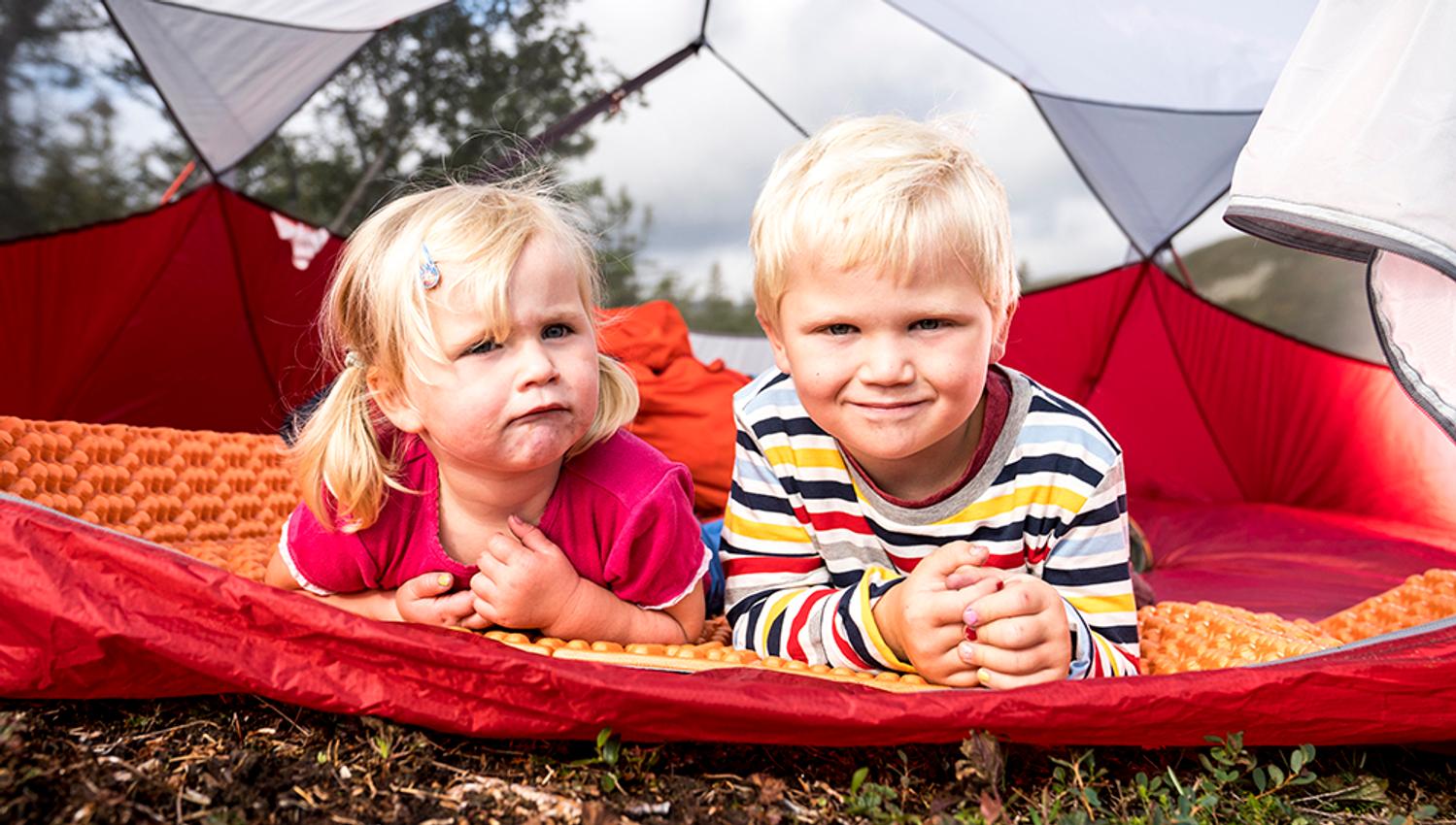 liten gutt og jente ligger i telt på vandretur til tretoppern i Bø