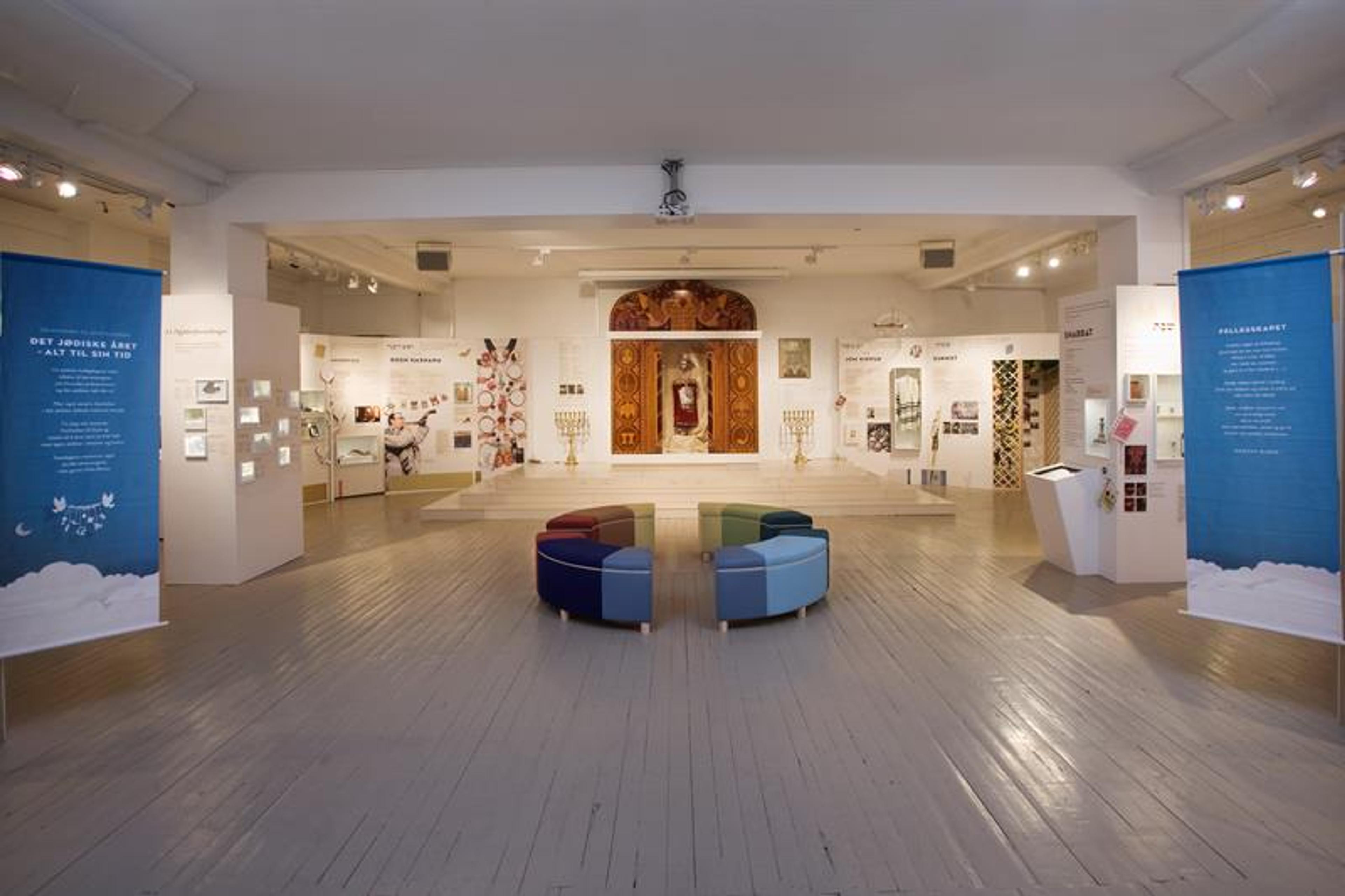 Interiør. Plakater langs veggene, sitteseksjon i midten av rommet.