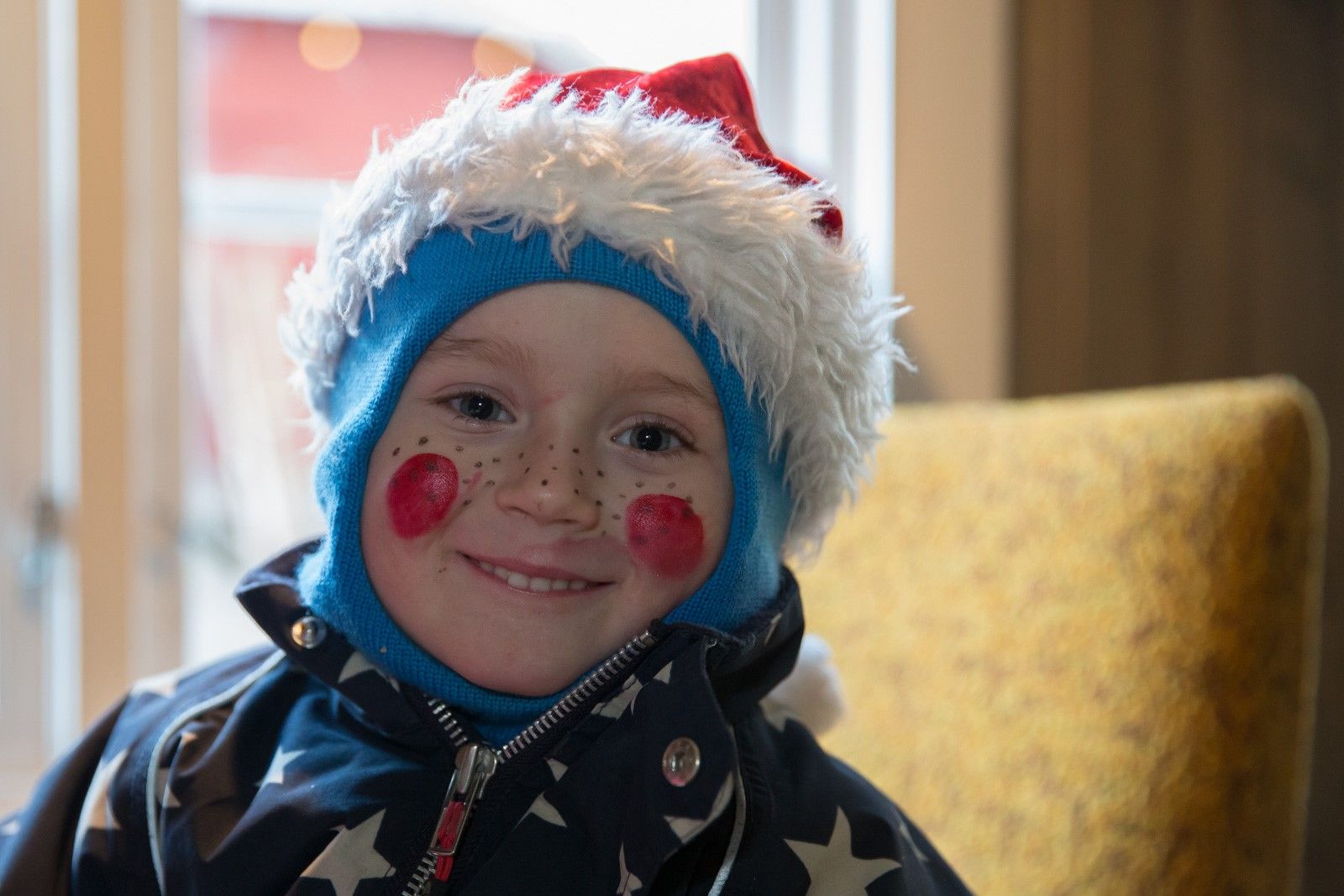 Cute little audience member with a Santa hat and painted roses on his cheeks