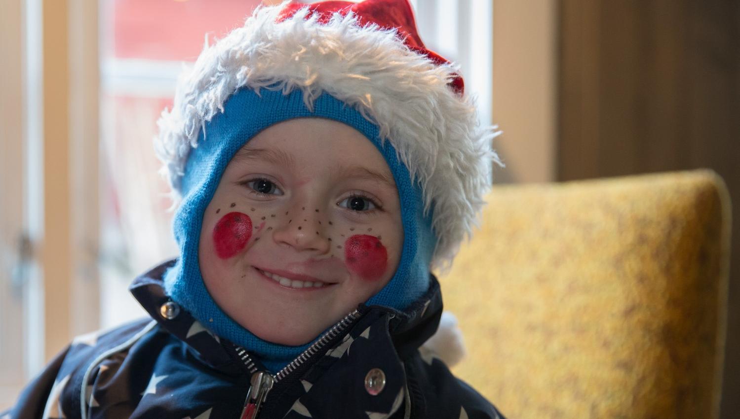 Cute little audience member with a Santa hat and painted roses on his cheeks