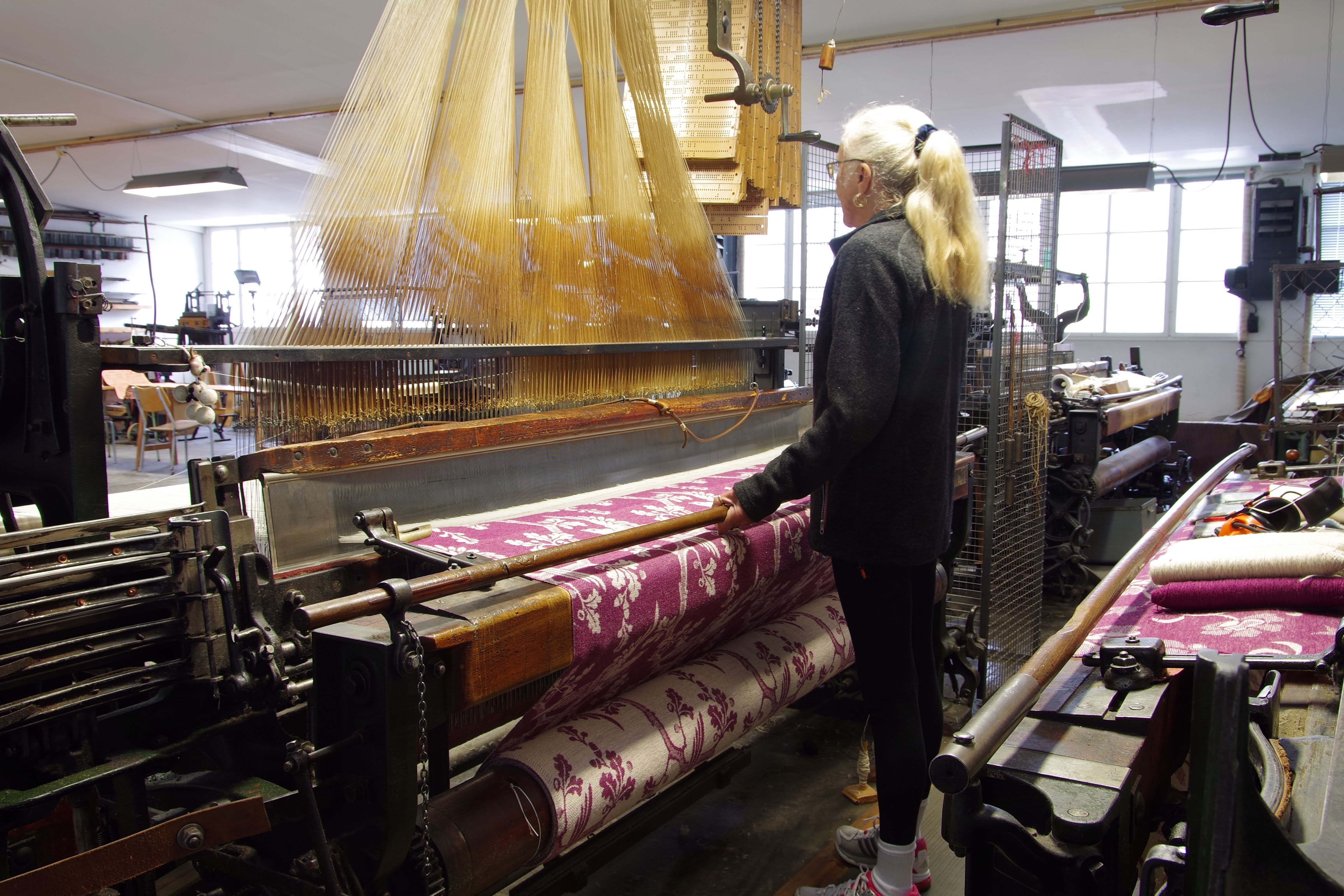 Woman with a ponytail working at the weaving machine.