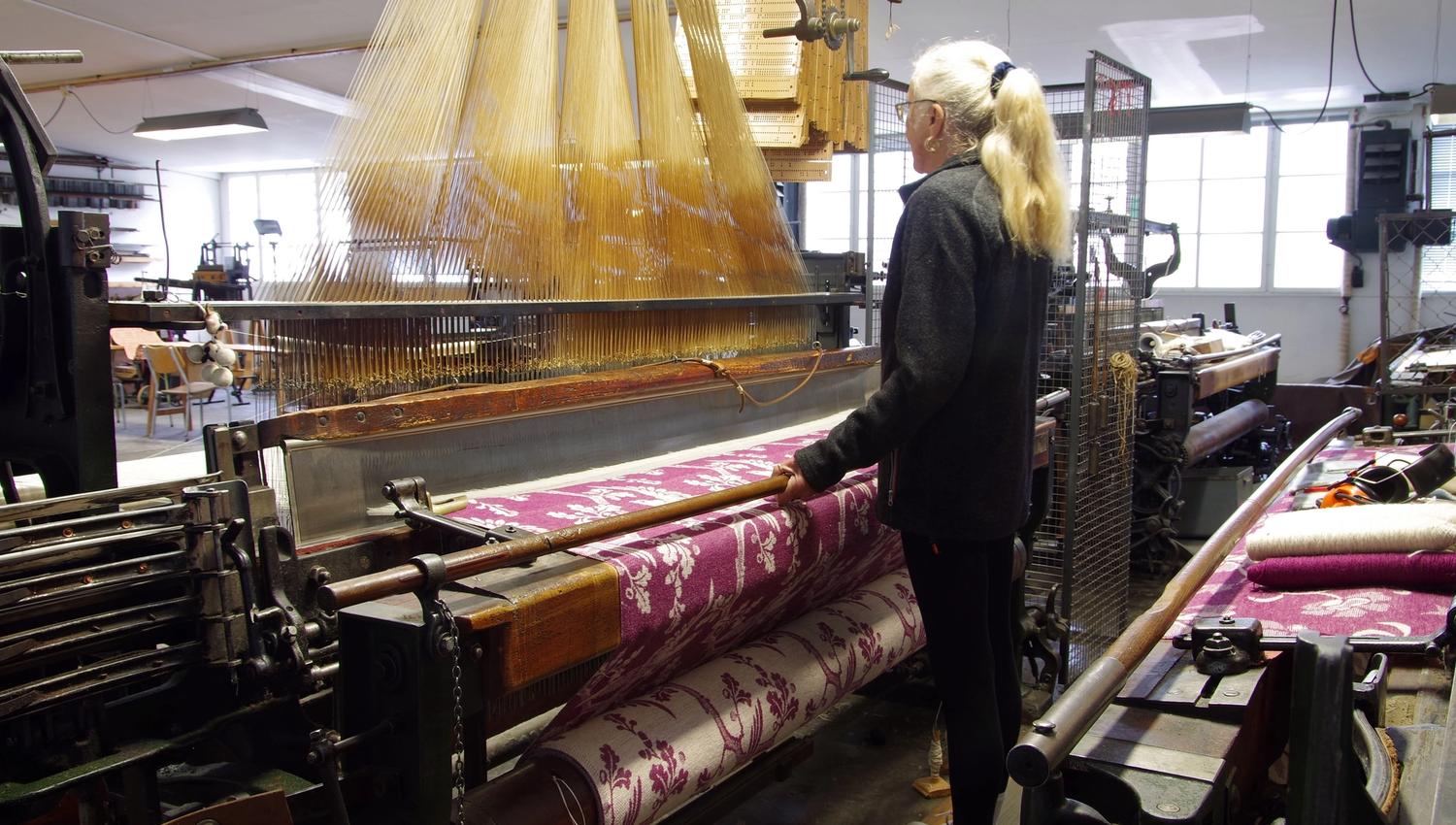 Woman with a ponytail working at the weaving machine.