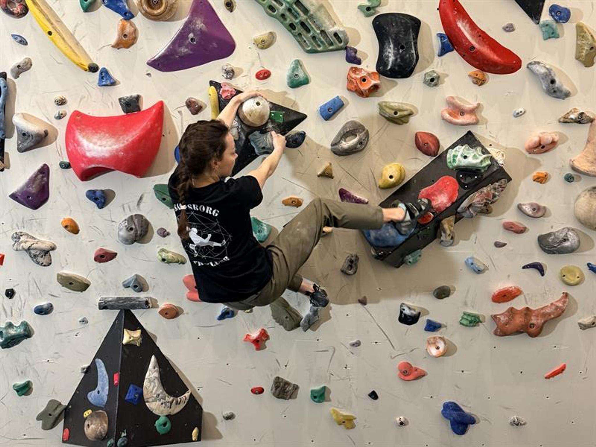 foto, en pesron klatrer på en klatrevegg