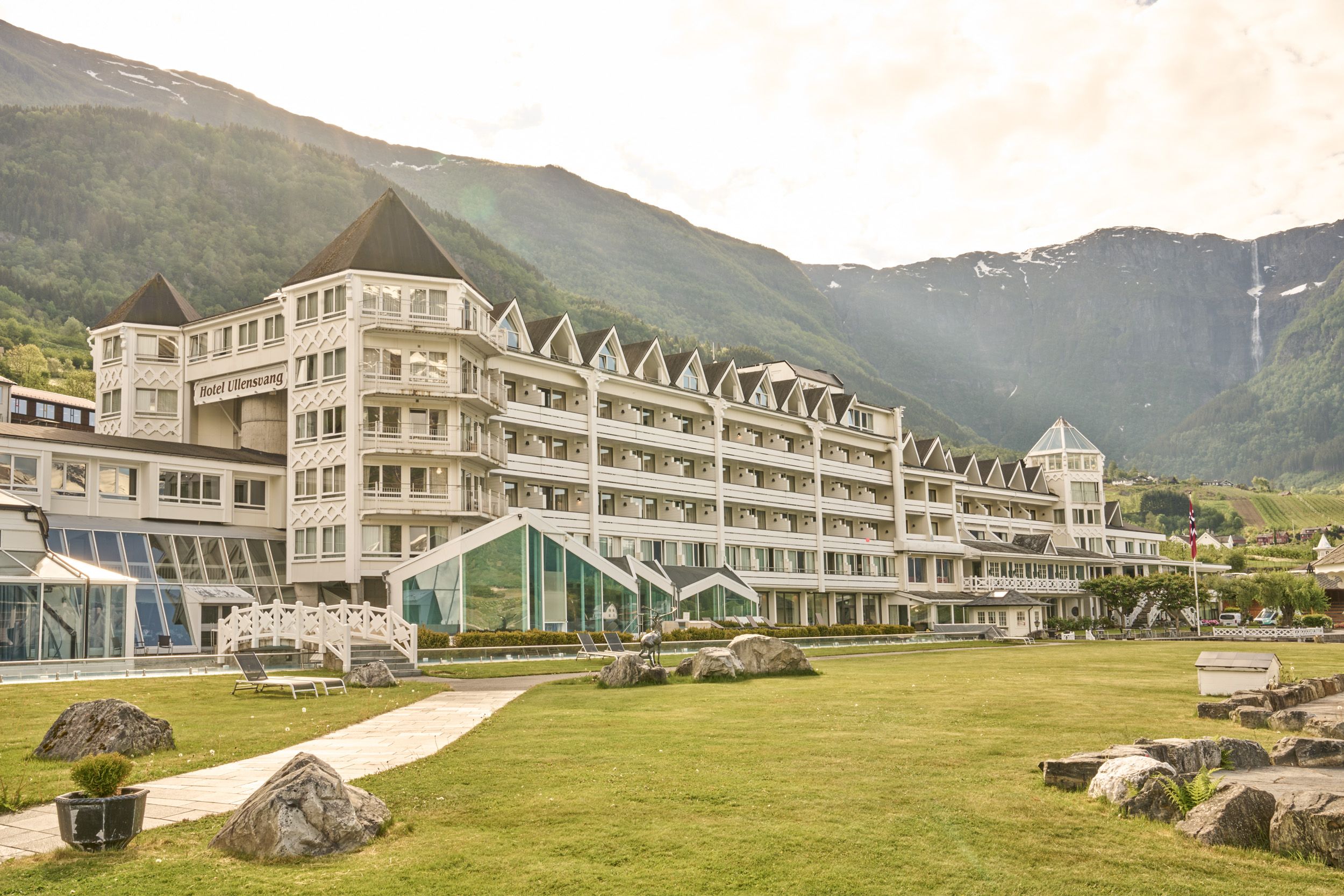 Hotel Ullensvang ligg vakkert til ved Hardangerfjorden, omkransa av grøne hageområde og majestetiske fjell.