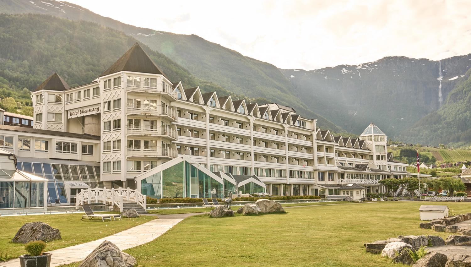 Hotel Ullensvang ligg vakkert til ved Hardangerfjorden, omkransa av grøne hageområde og majestetiske fjell.