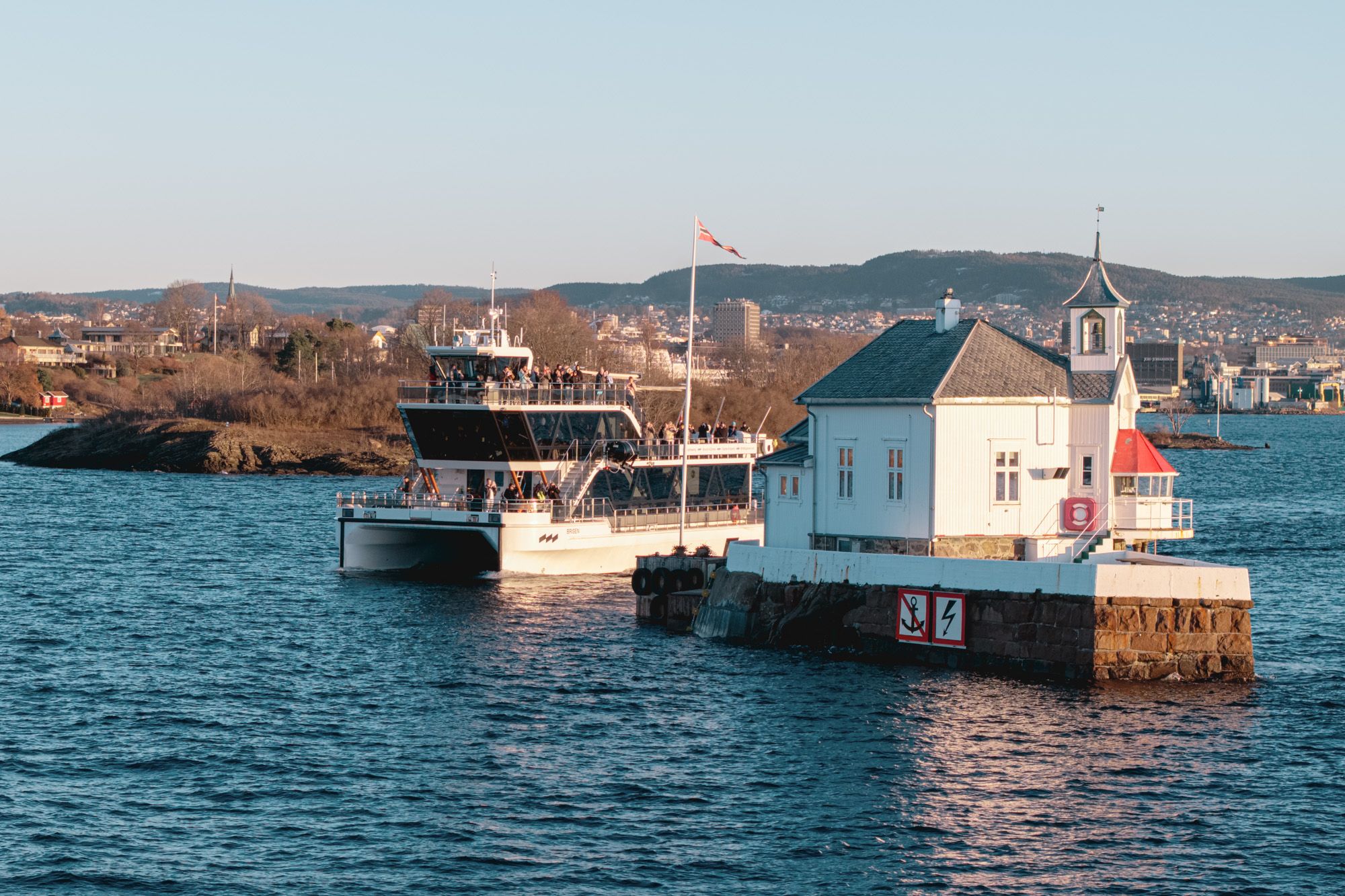 The boat passing between a lighthouse and an island in the Oslofjord