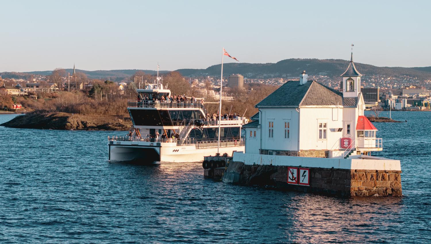 The boat passing between a lighthouse and an island in the Oslofjord
