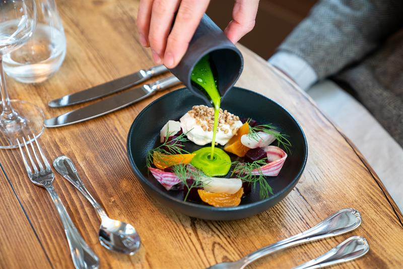 Matrett med fisk og grønnsaker på sort tallerken