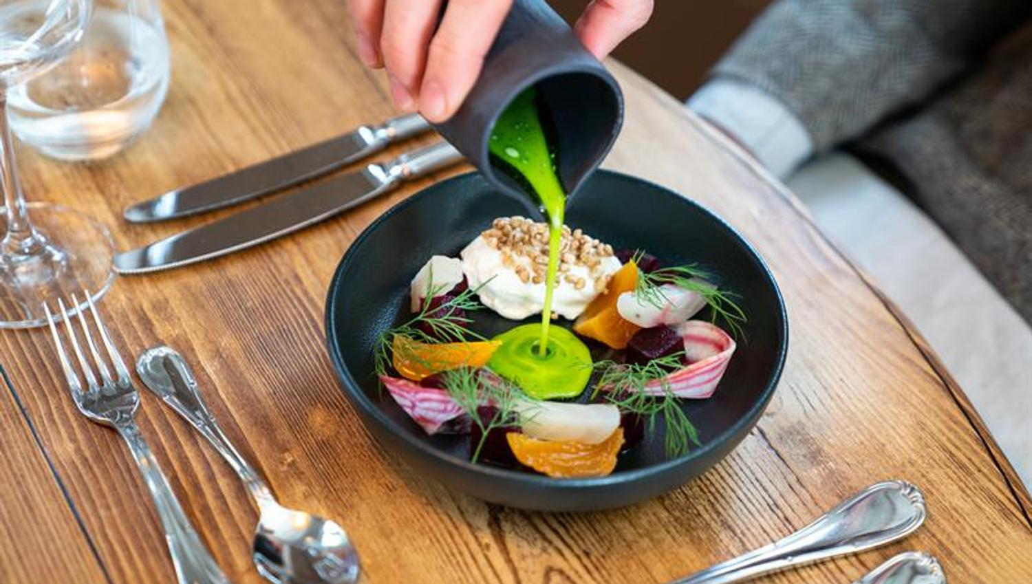 Matrett med fisk og grønnsaker på sort tallerken