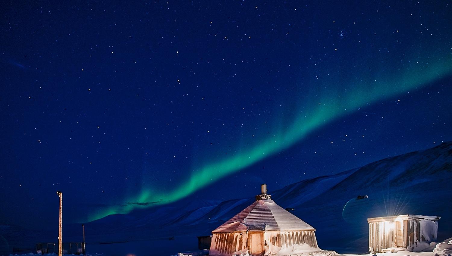 A strip of northern lights shining above Camp Barentz