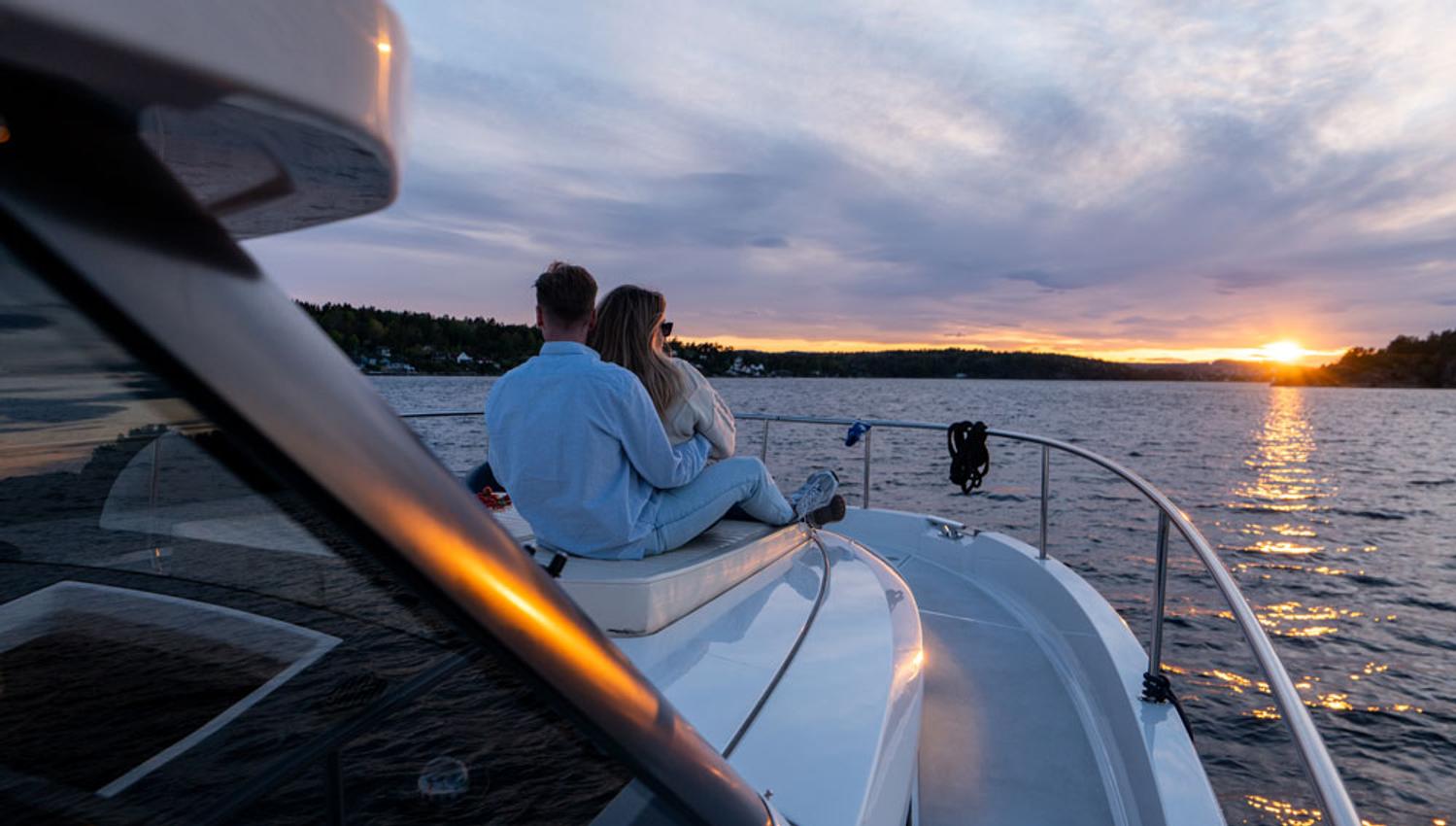 par sitter på dekk og nyter solnedgangen