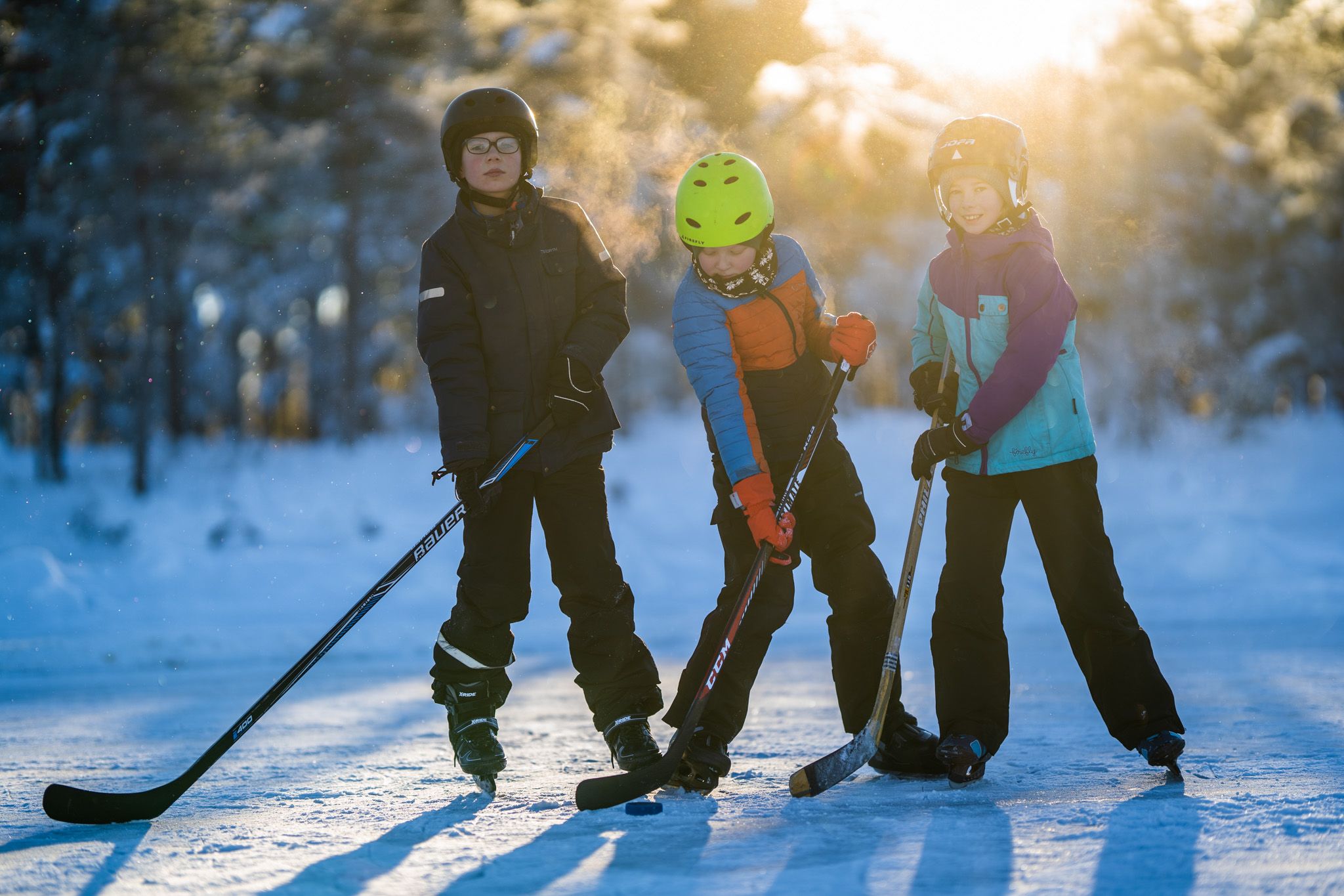tre barn med ishocky køller