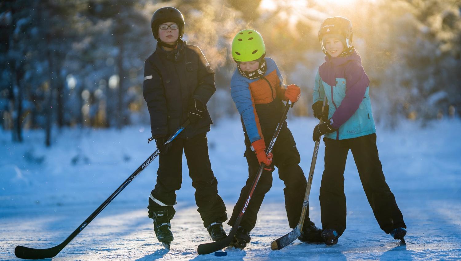tre barn med ishocky køller