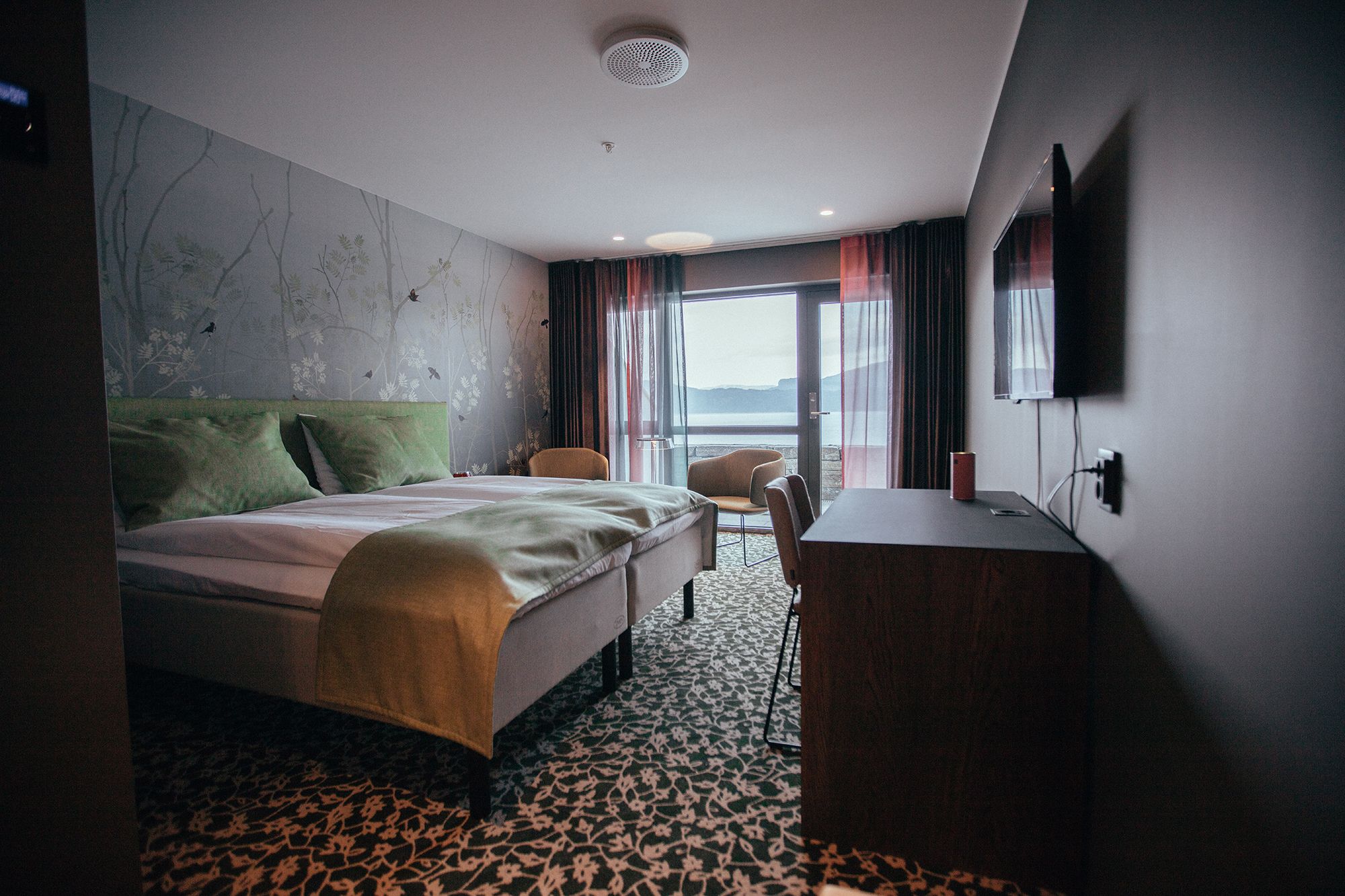 Hotel room at Hardanger House with green decor and fjord view.