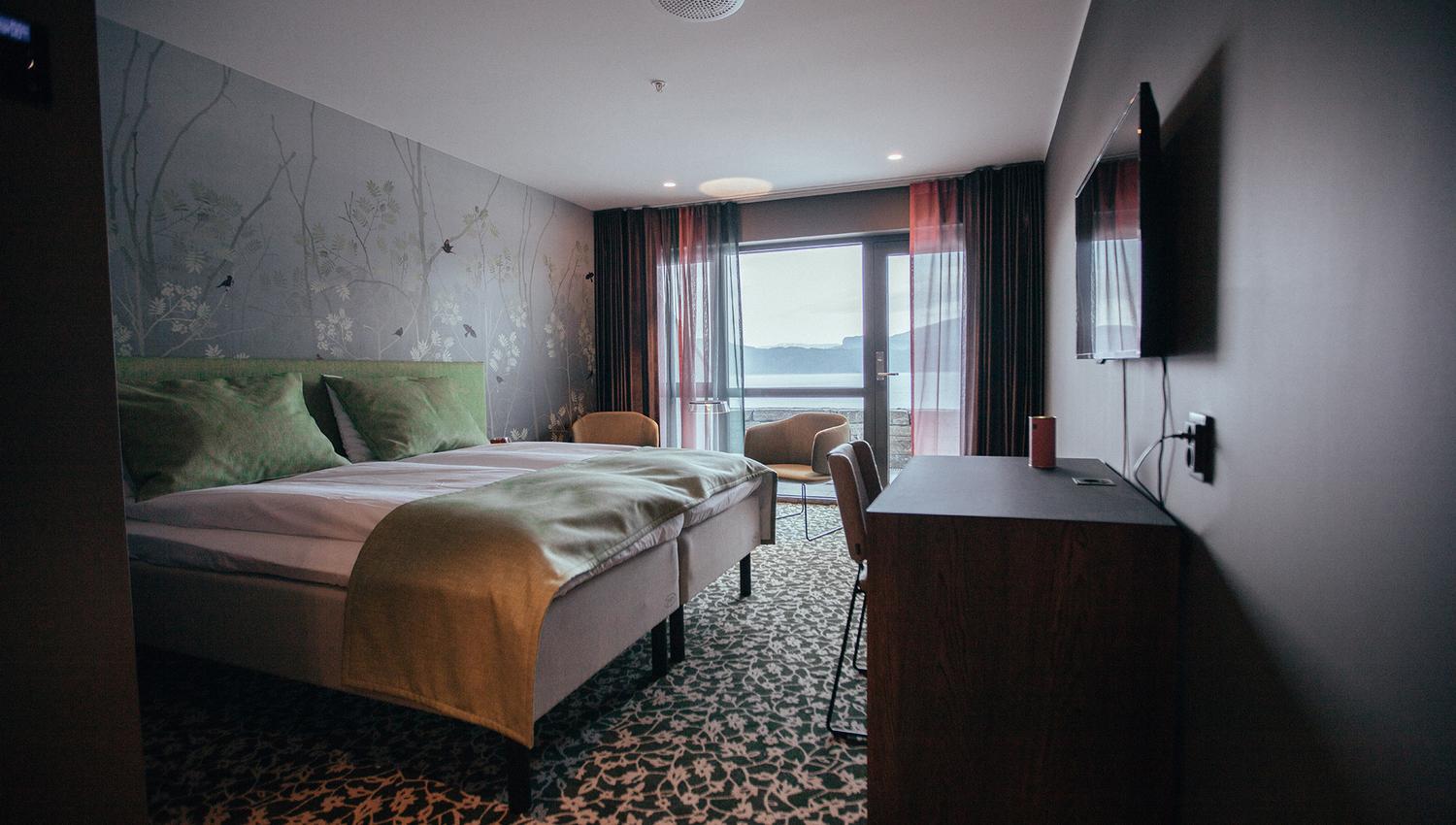 Hotel room at Hardanger House with green decor and fjord view.