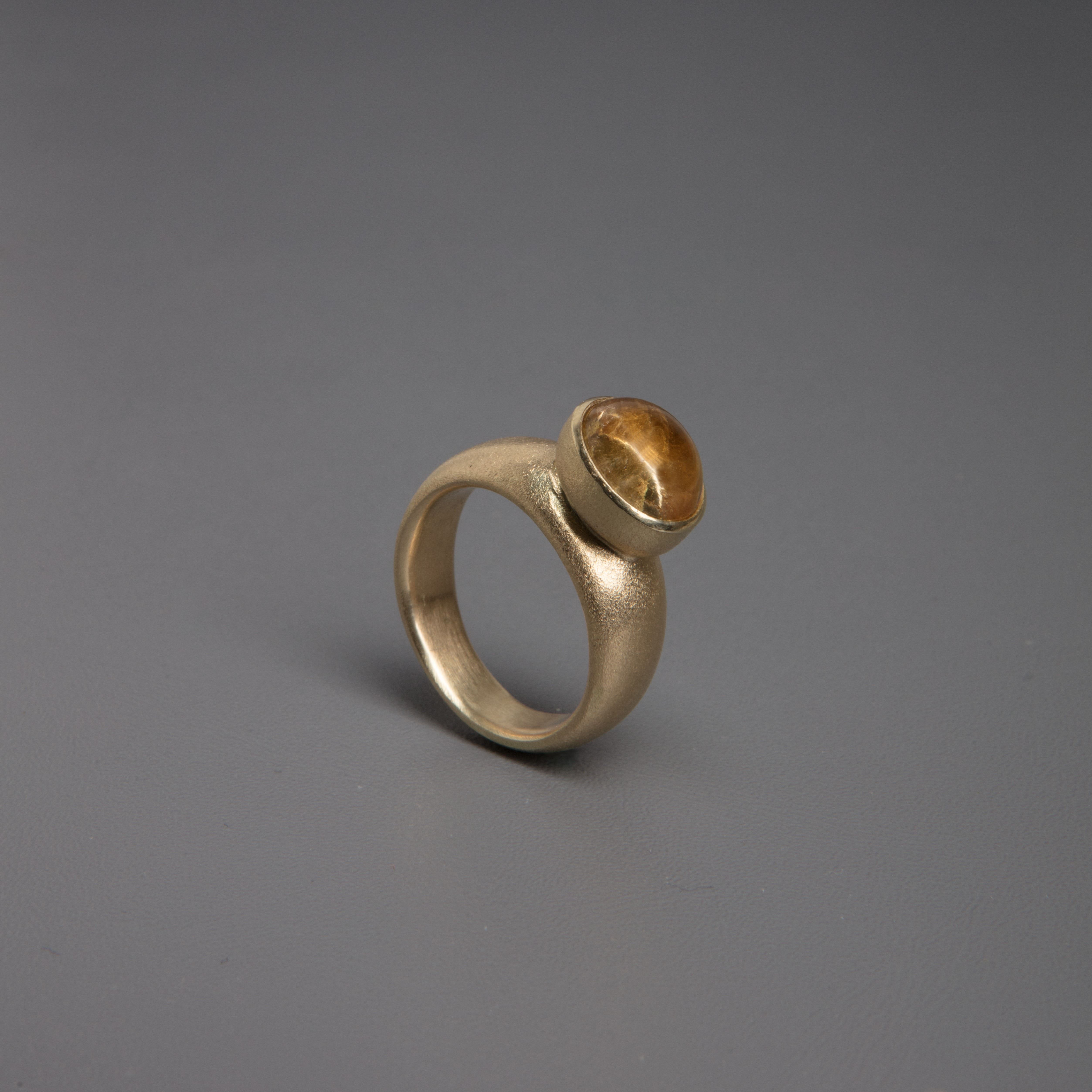 Ring med brun rund edelsten på grå bakgrunn