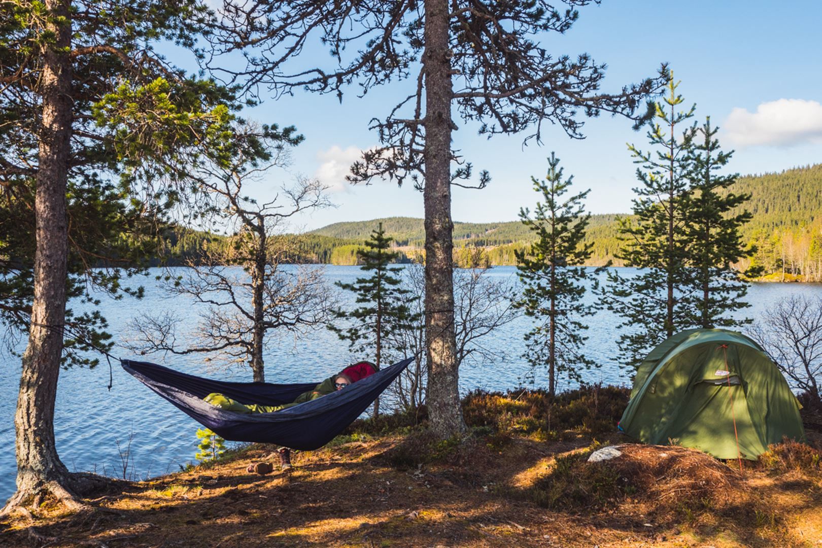 A hammock and a tent by a lake.