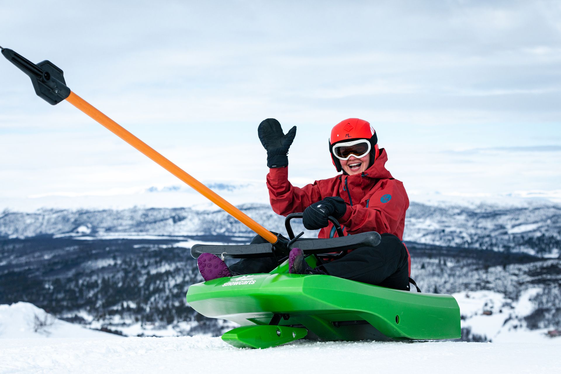 En gutt som vinker mens han tar heisen opp med det grønne akebrettet.