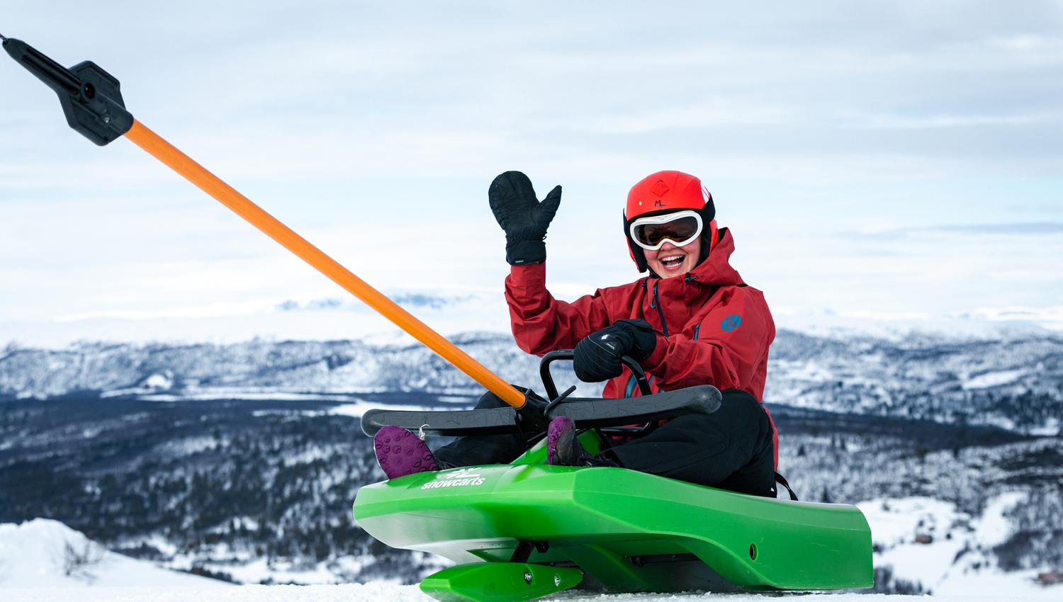 En gutt som vinker mens han tar heisen opp med det grønne akebrettet.