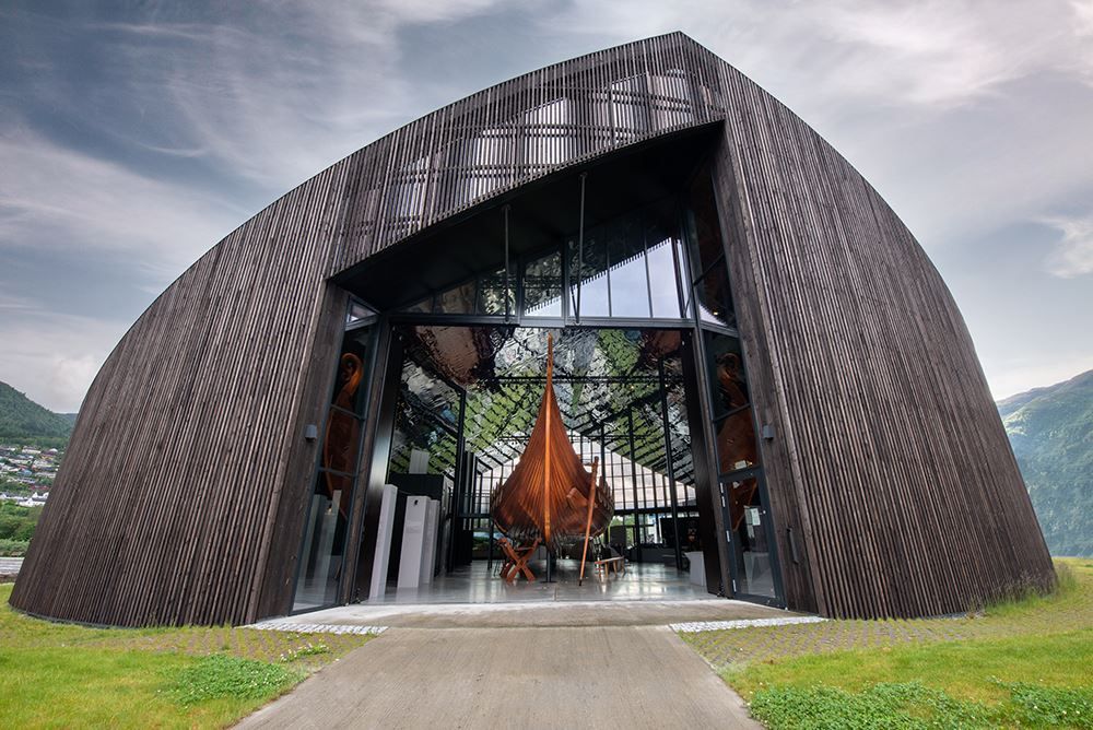 Det karakteristiske bygget til Sagastad Vikingsenter på Nordfjordeid, sett mot fjell og skyet himmel..