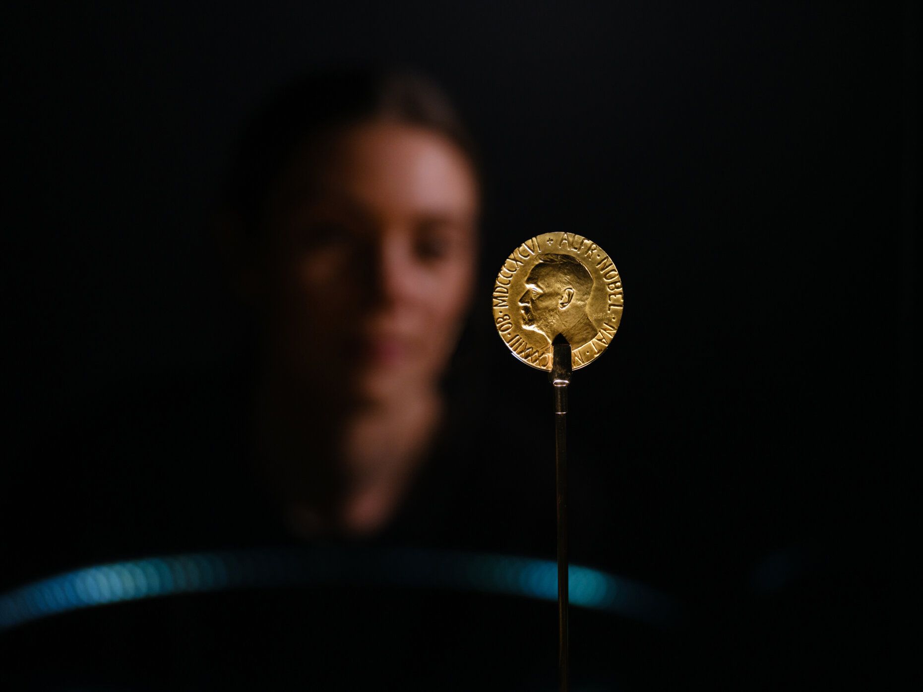 Detaljbilde av medalje i gull og ansikt i bakgrunn.