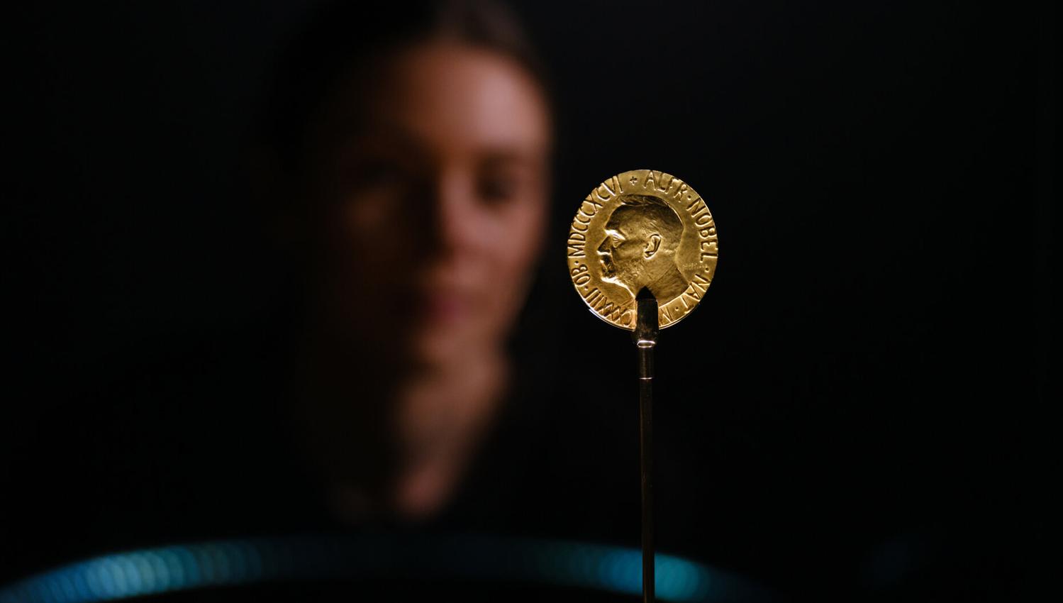 Detaljbilde av medalje i gull og ansikt i bakgrunn.