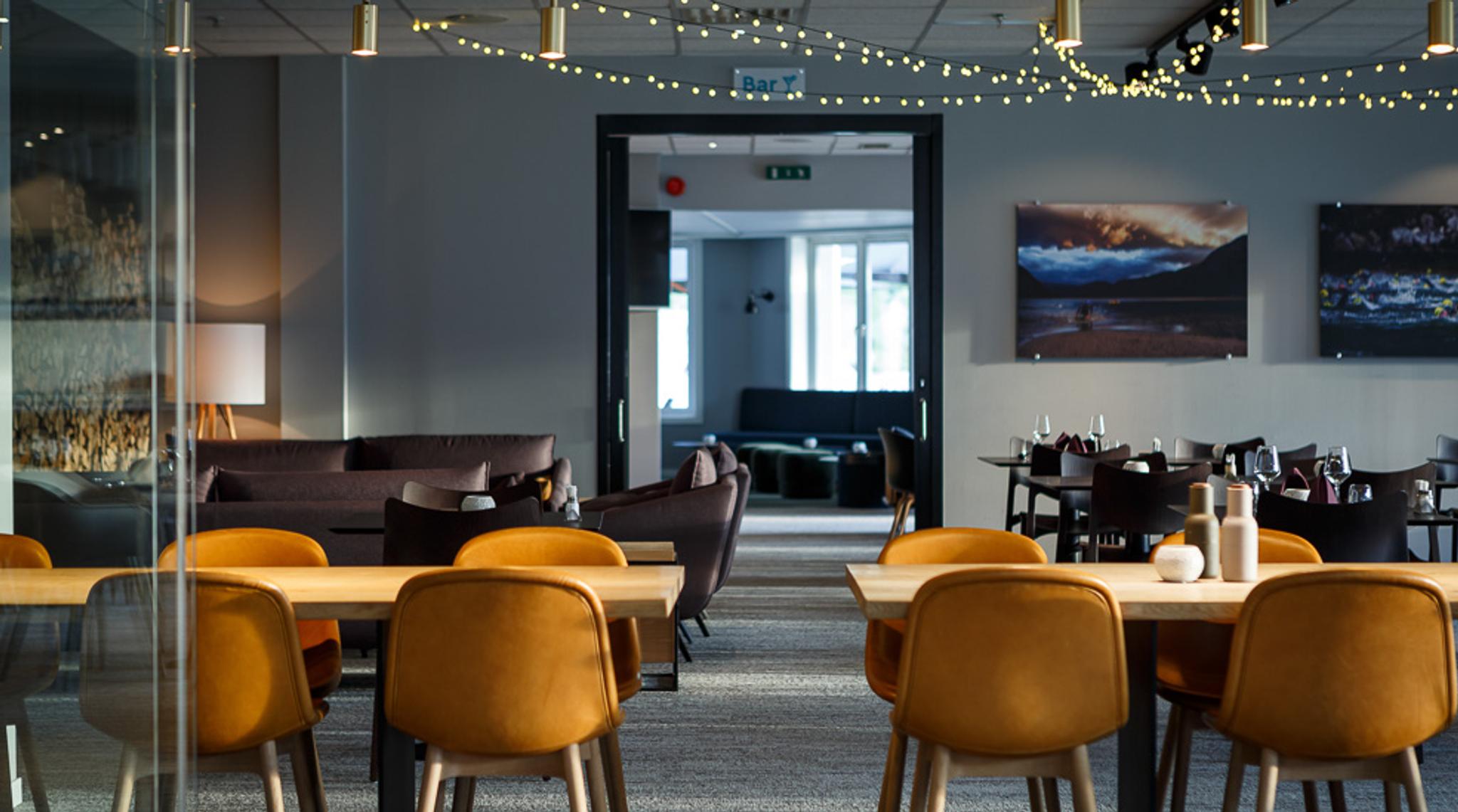 The diningroom at the restaurant with tables, chairs and light chains hanging in the ceiling.