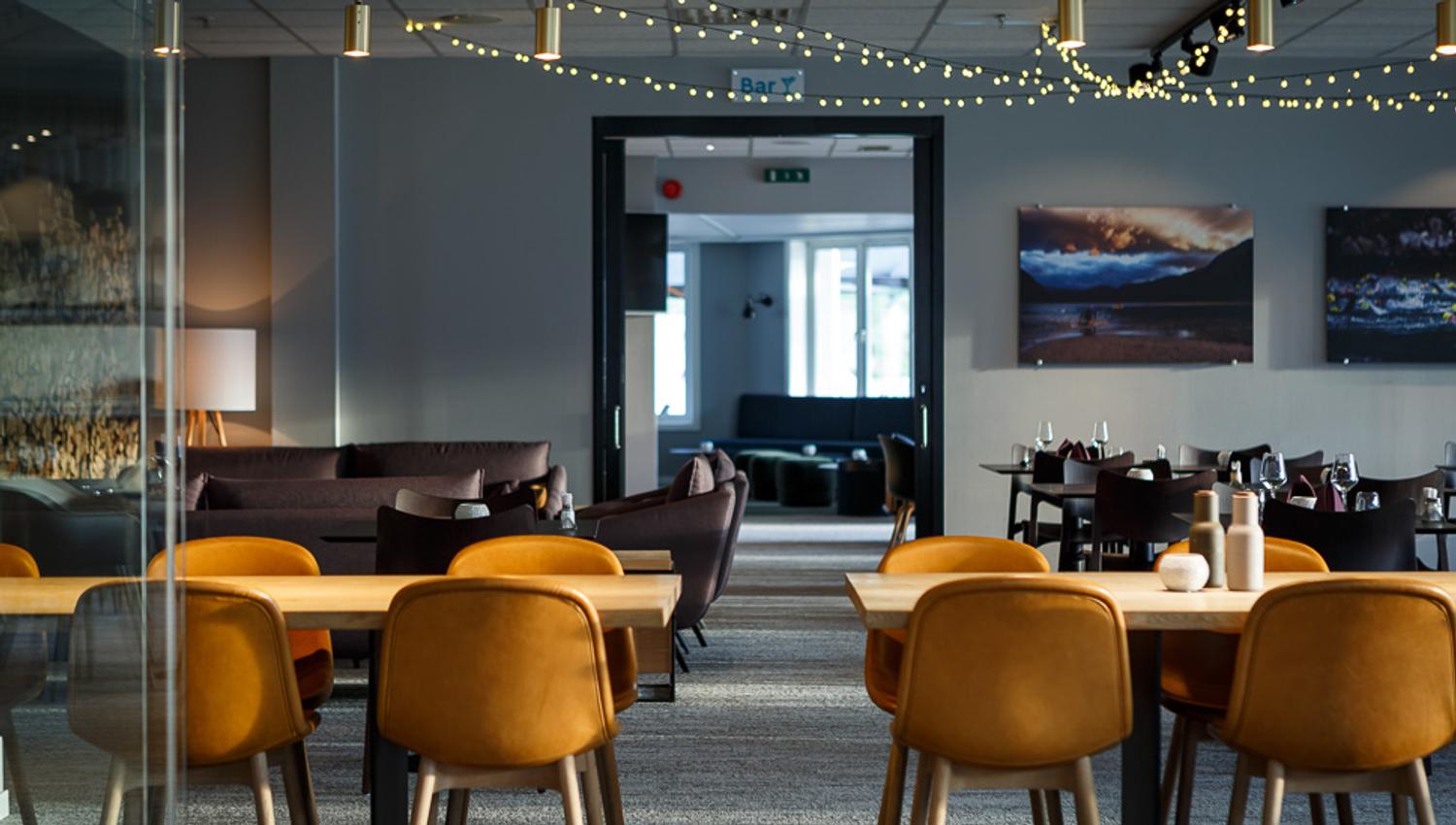Spisesalen på restauranten med bord, stoler og lyslenker hengende i taket.