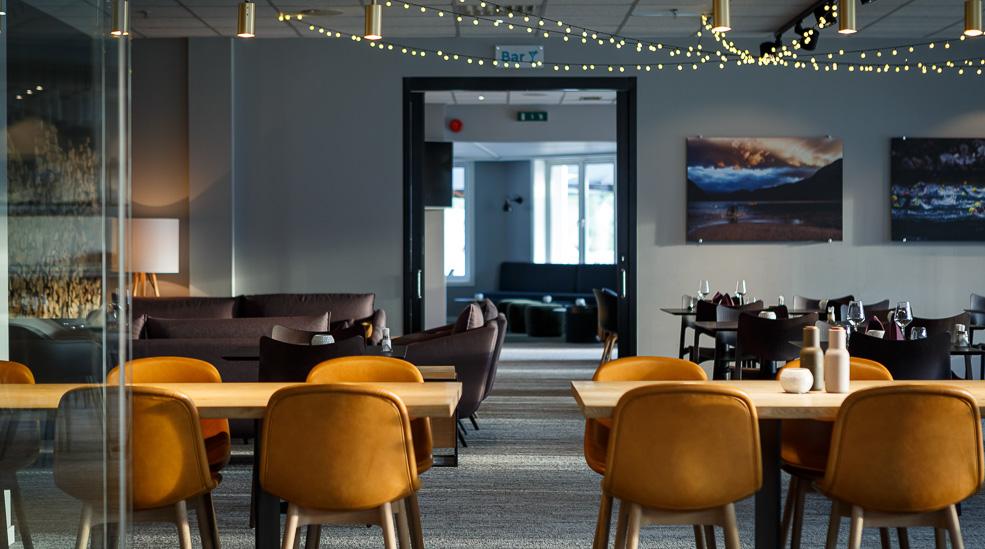 The diningroom at the restaurant with tables, chairs and light chains hanging in the ceiling.